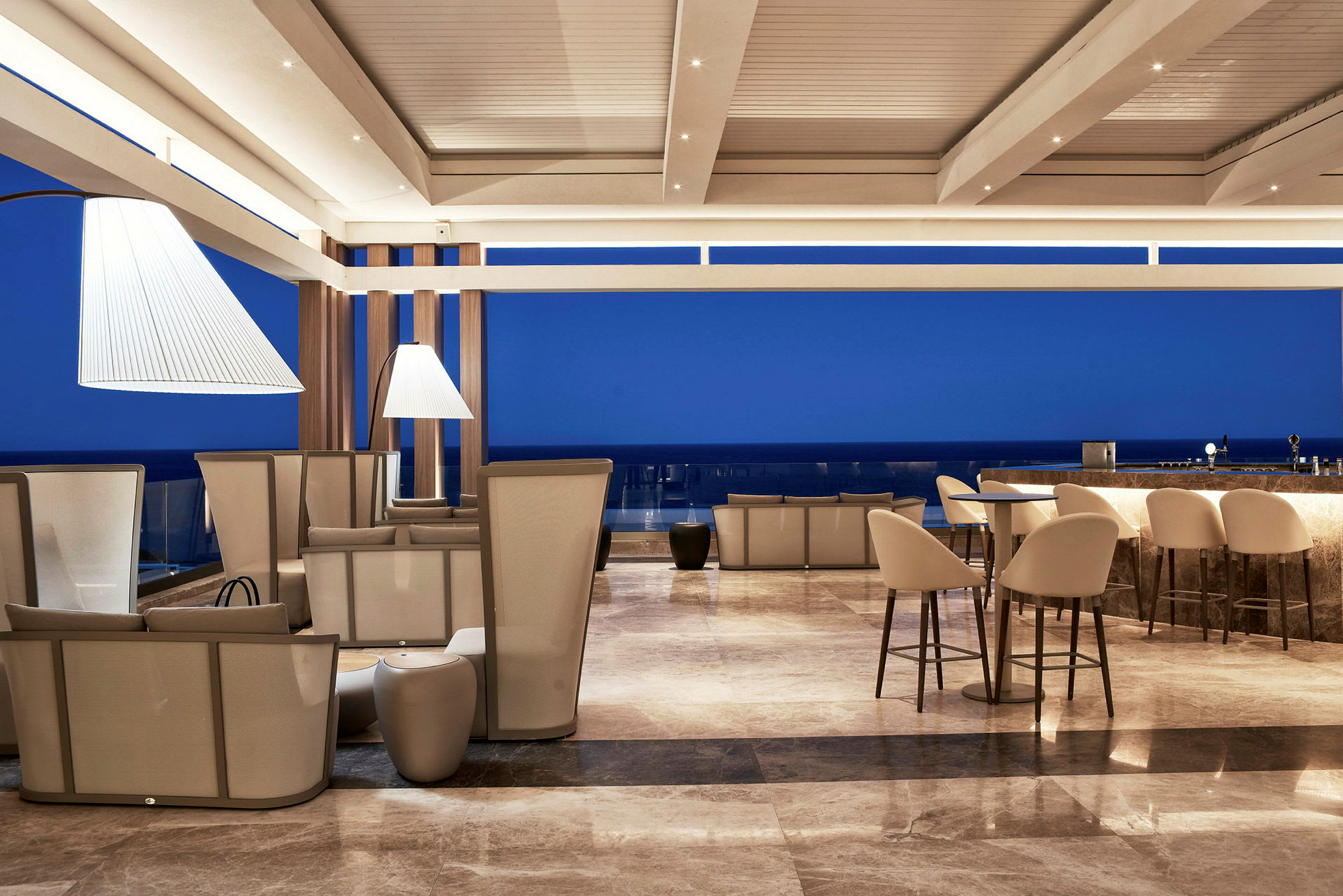 En modern lounger med sittplatser och en bardisk, med blå himmel i bakgrunden. (AI-genererad text)