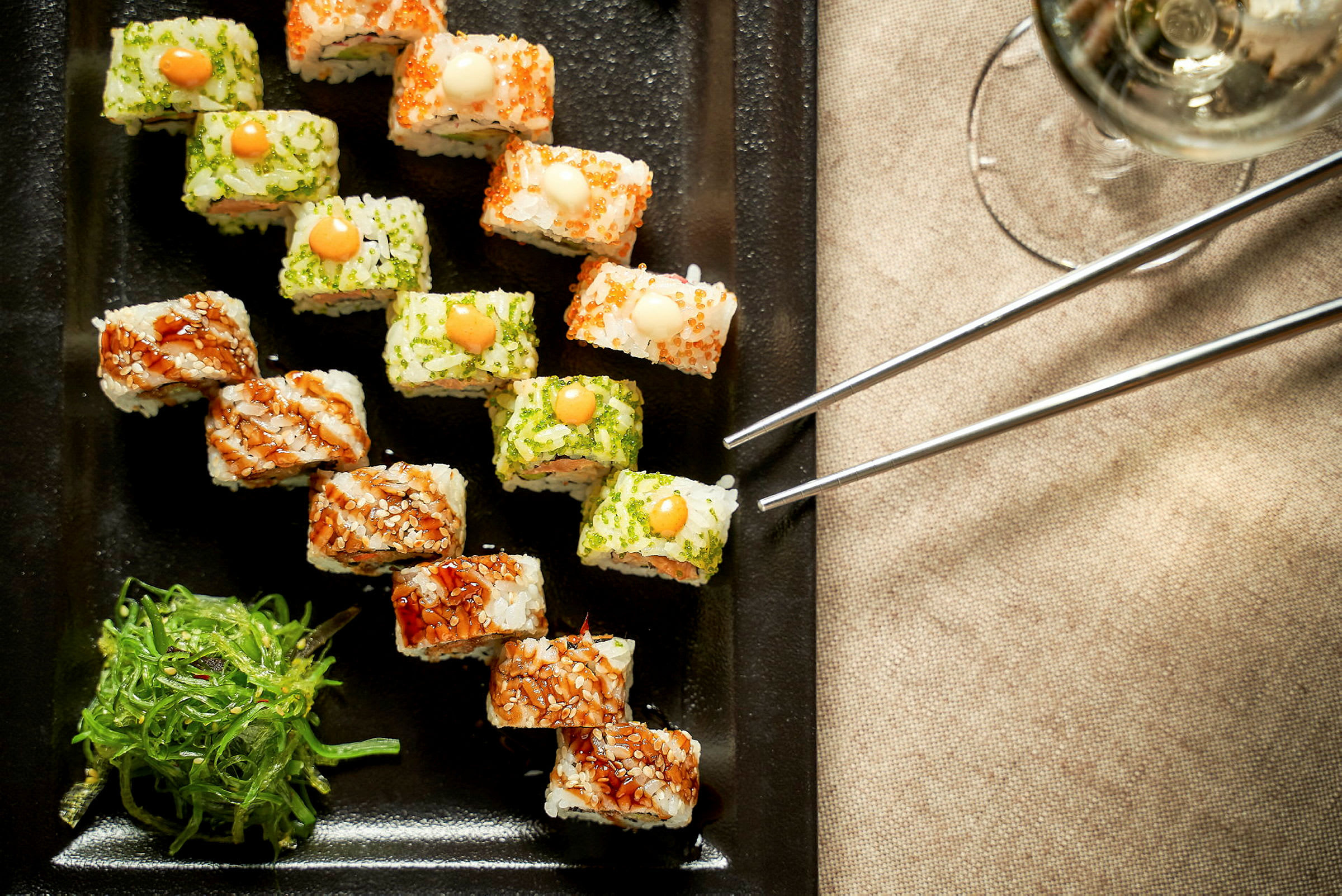 Sushi serverad på en svart tallrik med sjögrässallad vid sidan om. (AI-genererad text)