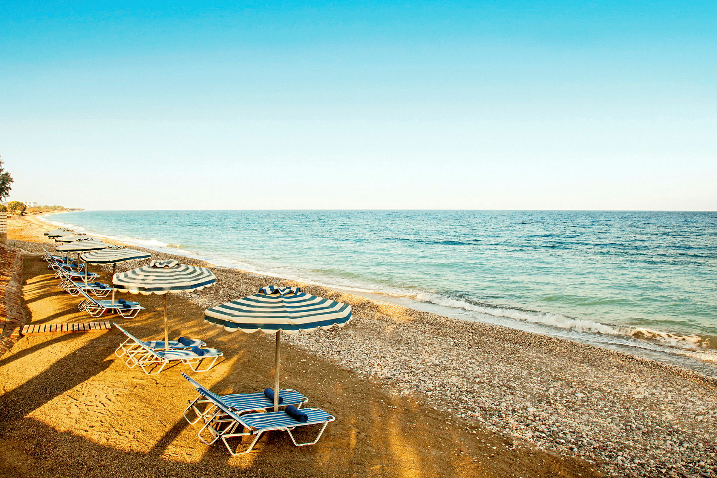 Strand med solstolar och parasoller nära havet. (AI-genererad text)