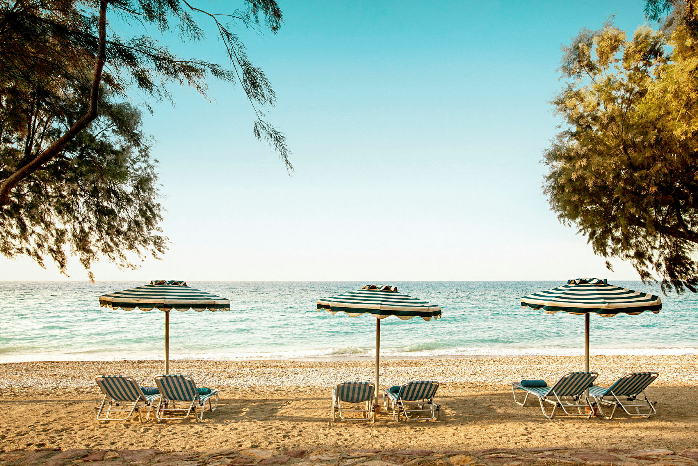 Strand med parasoller och solstolar vid havet. (AI-genererad text)