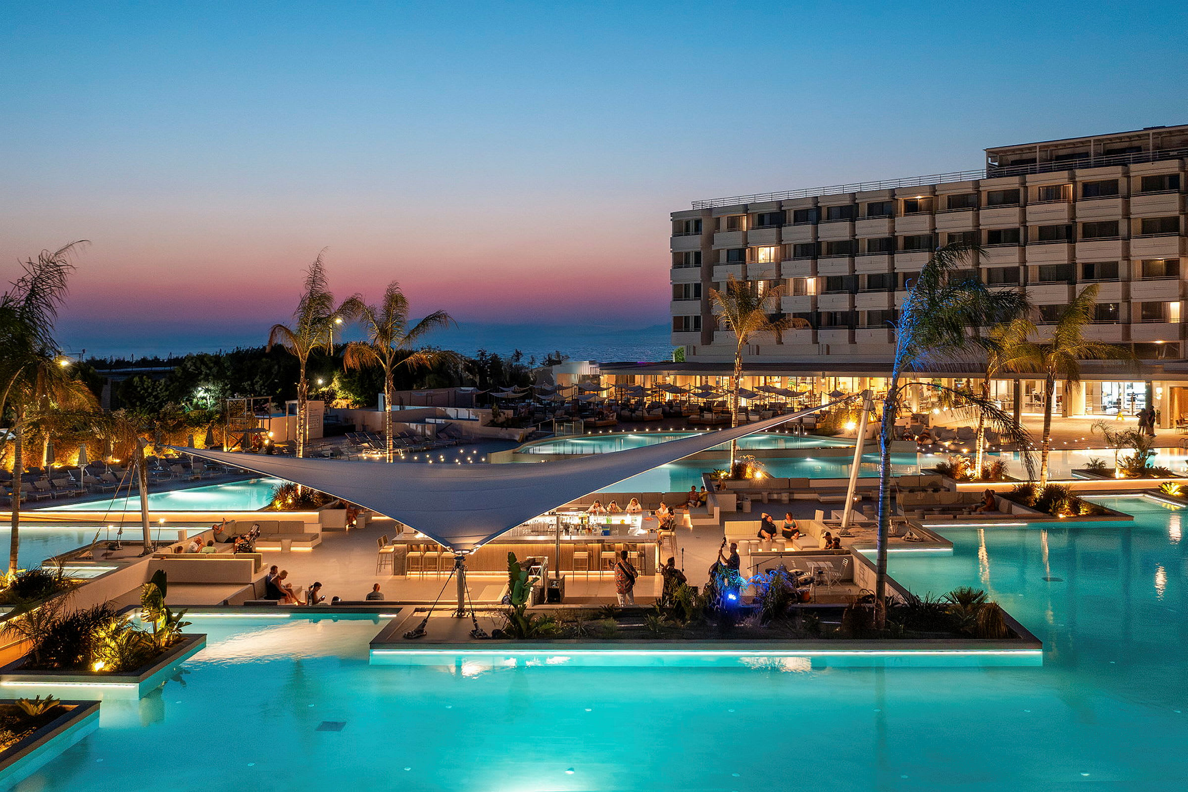Lyxig hotellpoolområde med belysning och sittplatser under skymningen. (AI-genererad text)