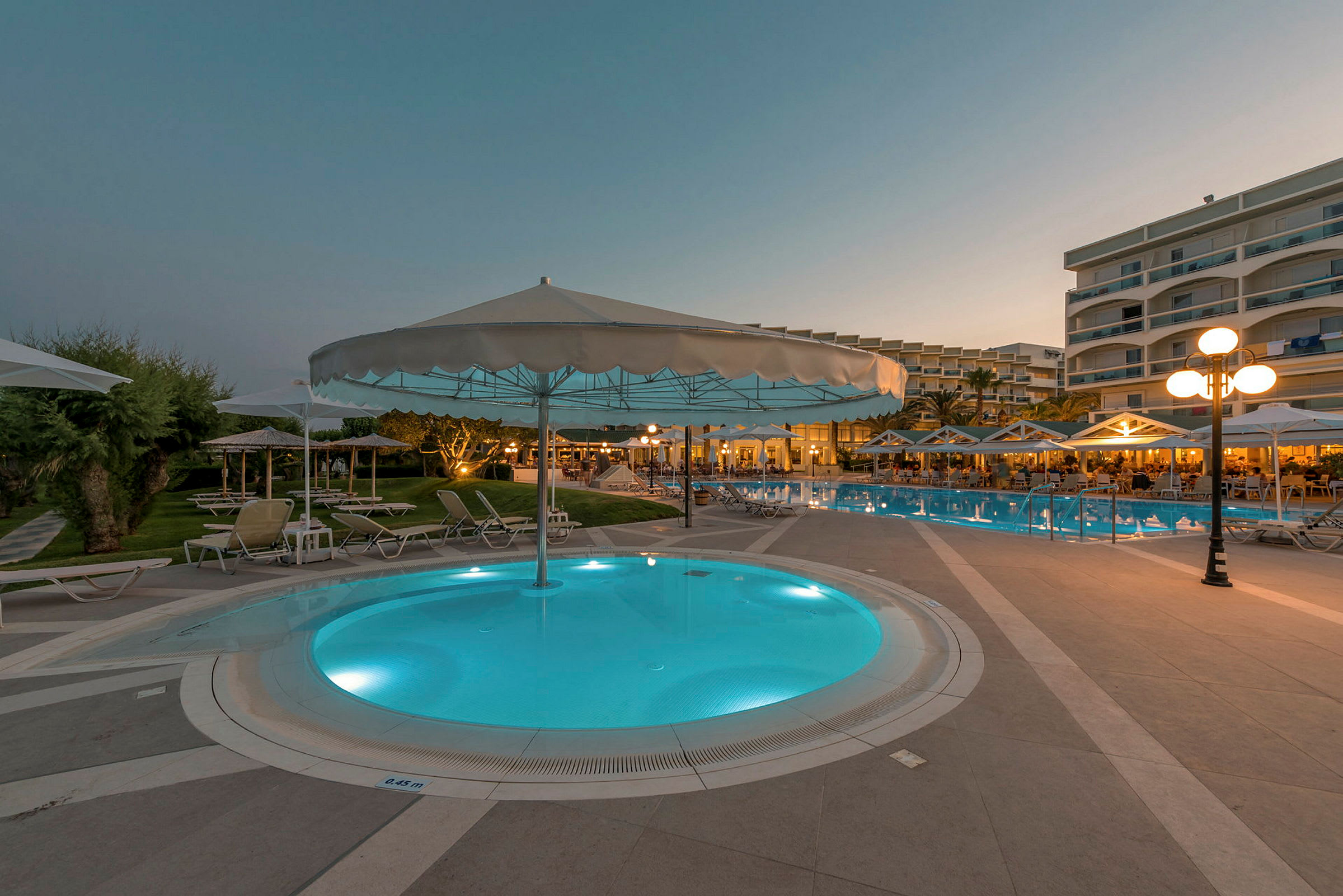 Hotellpoolområde på kvällen med parasoll och solstolar. (AI-genererad text)
