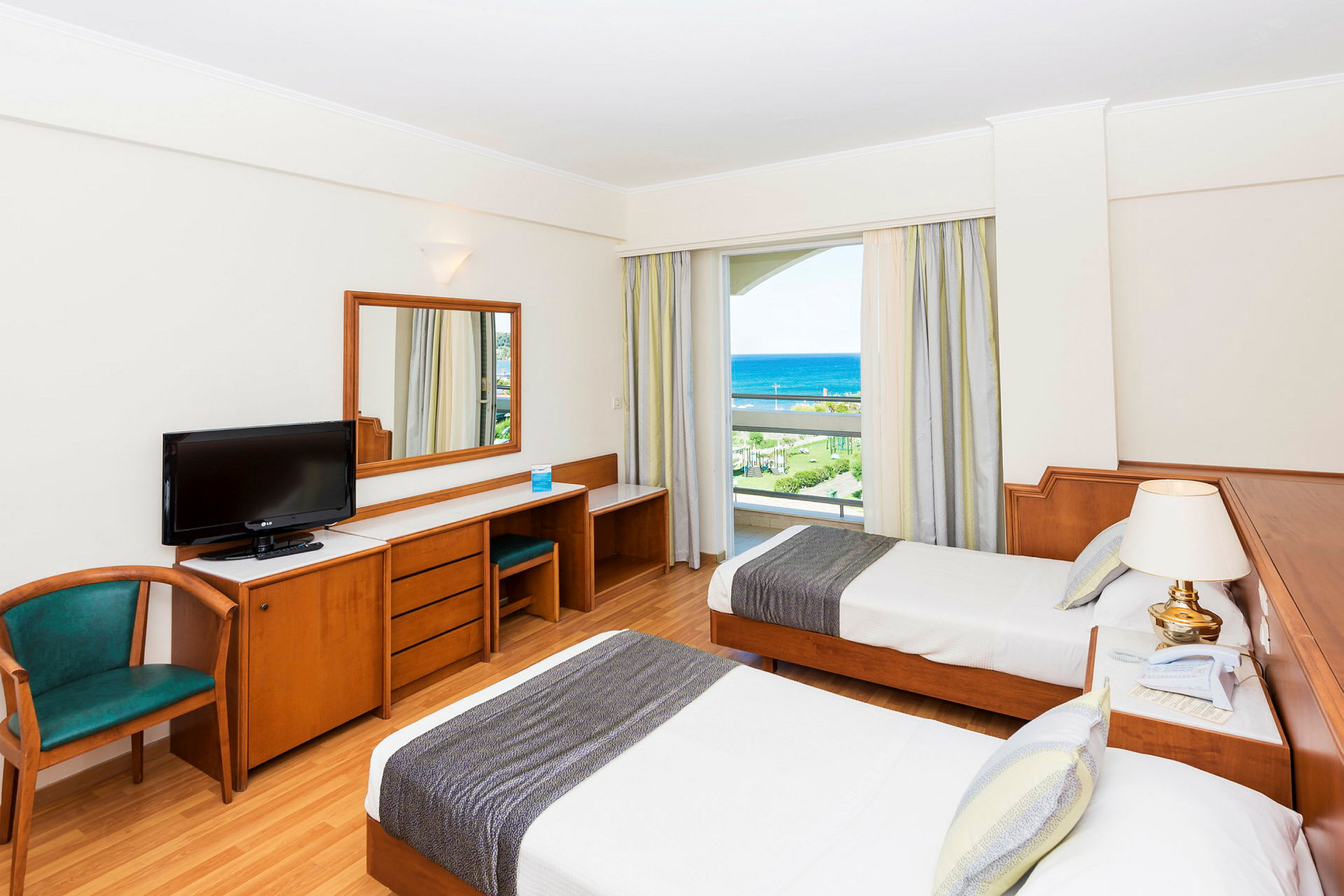 Hotelrum med två enkelsängar, skrivbord, stol och havsutsikt. (AI-genererad text)