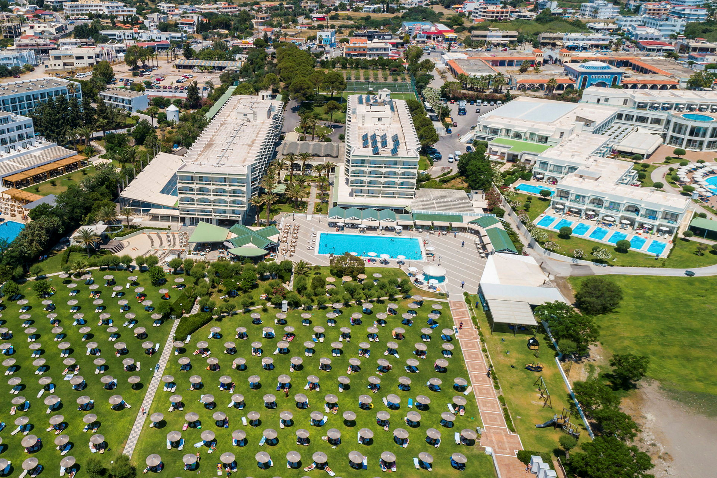 Flygbild över hotellkomplex med pooler, byggnader och gröna områden. (AI-genererad text)