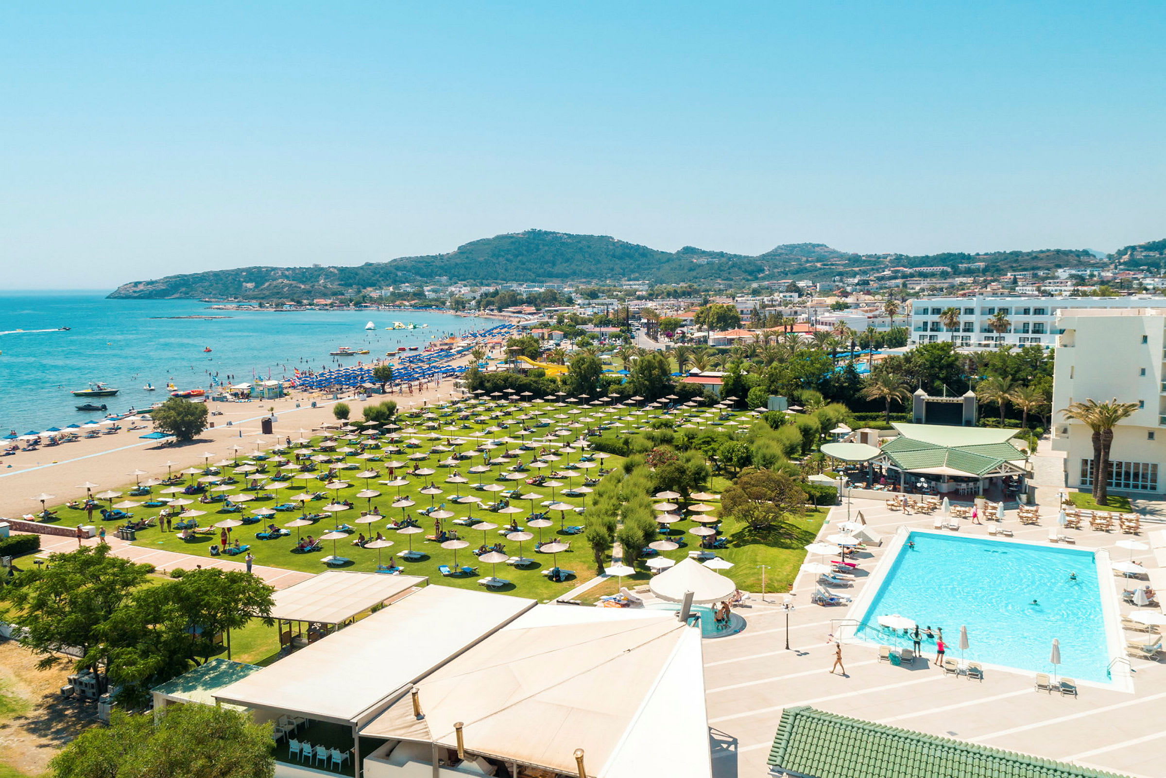 Poolområde framför hotell med utsikt över stranden och havet. (AI-genererad text)