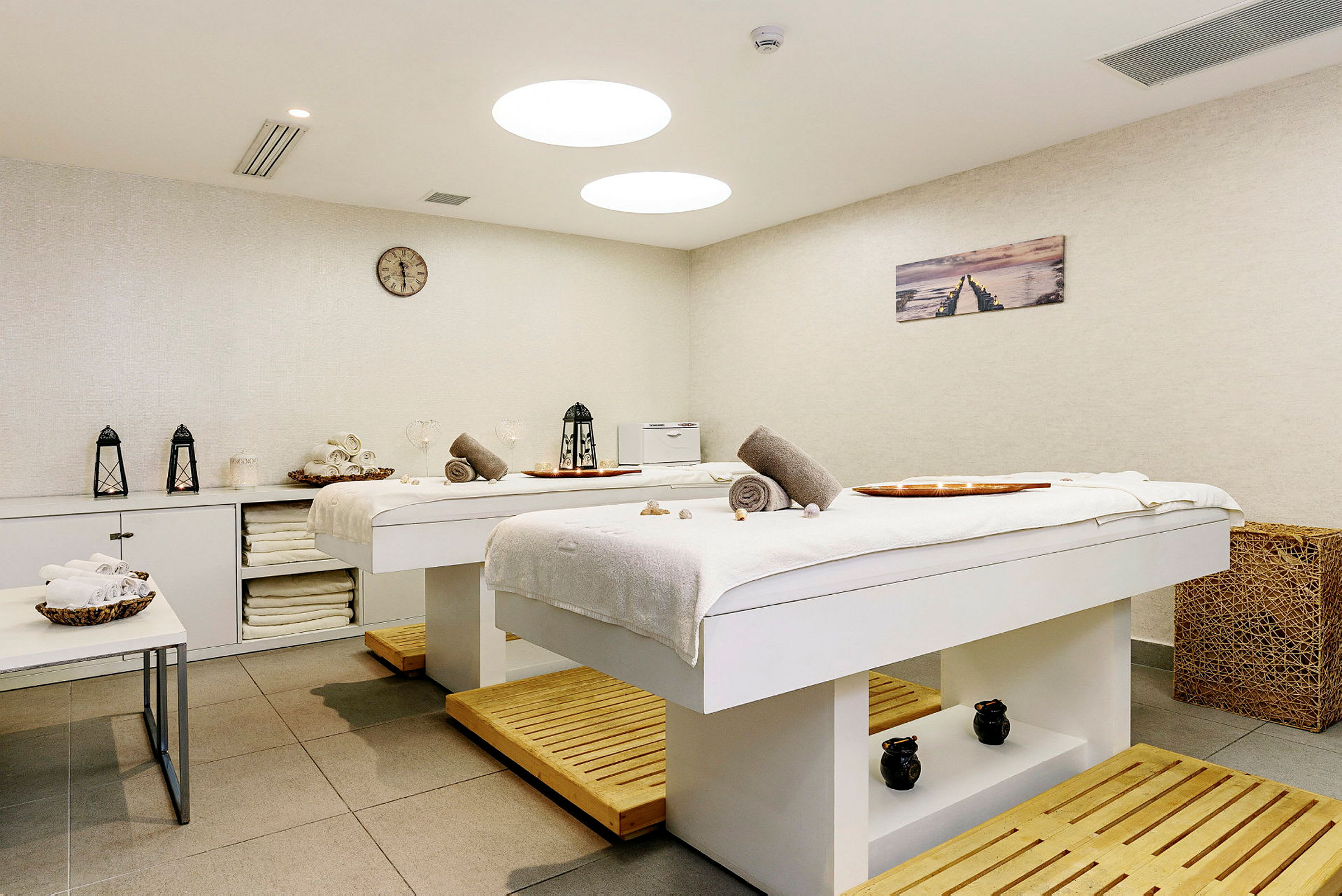 Två massagebord i ett ljus och inbjudande behandlingsrum. (AI-genererad text)
