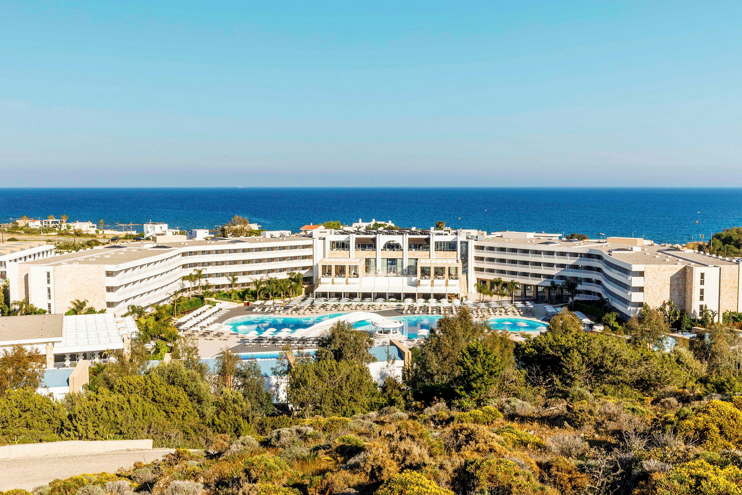 Vy över hotell med poolområde och havet i bakgrunden. (AI-genererad text)