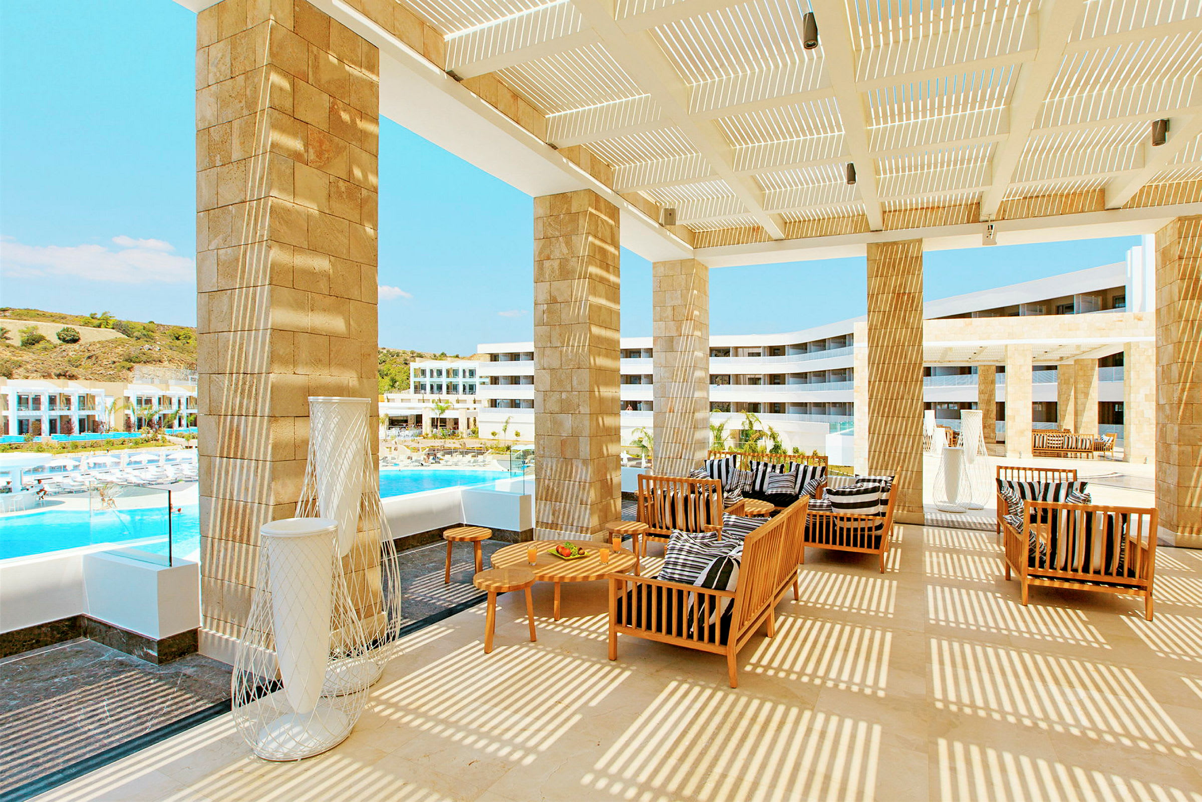 En terrass med möbler och utsikt över en pool och hotellbyggnader. (AI-genererad text)