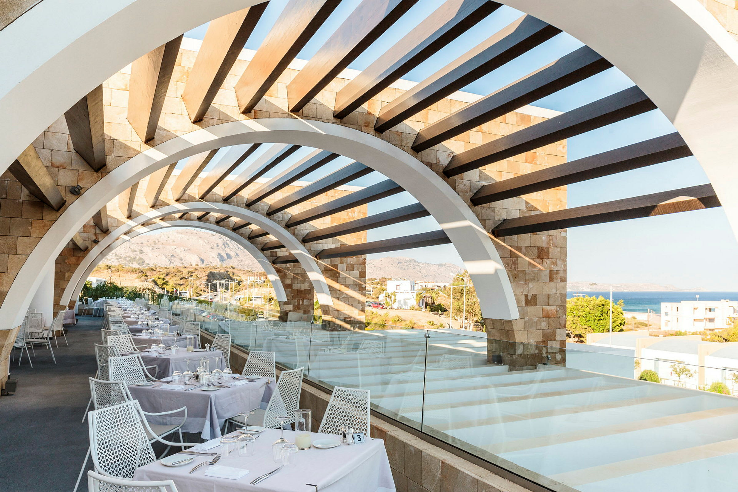 Restaurangterrass med bågformad pergola och havsutsikt. (AI-genererad text)