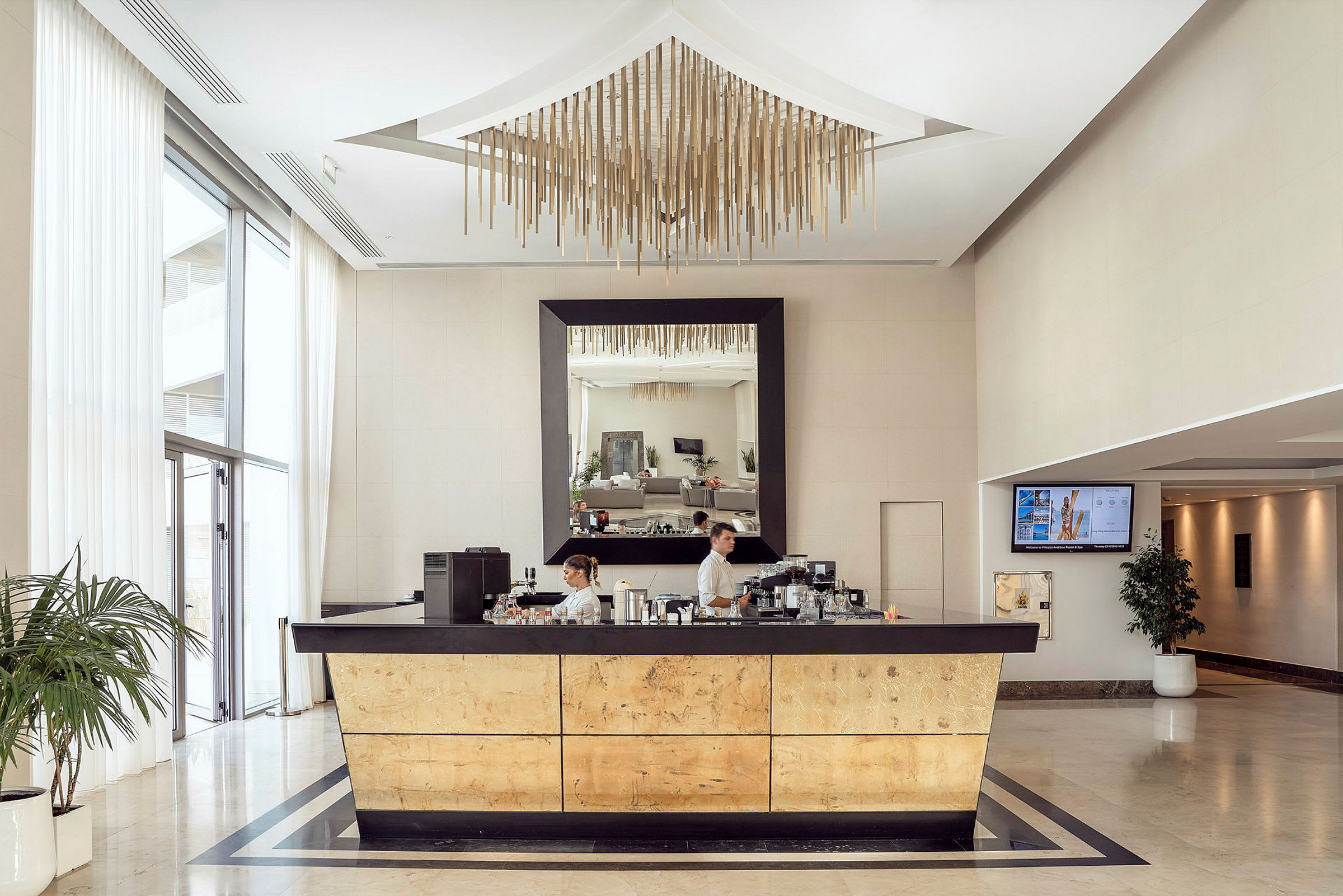 En lobby med en reception med gyllene detaljer och en spegel ovanför. (AI-genererad text)