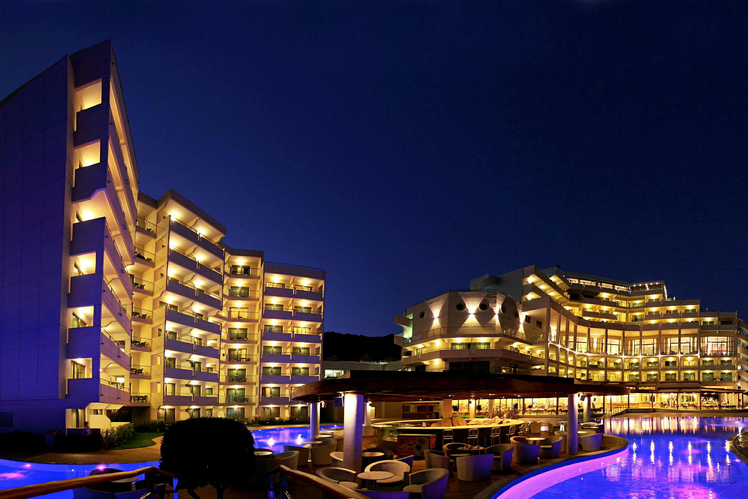 Hotell i nattbelysning med pool och uteplats. (AI-genererad text)