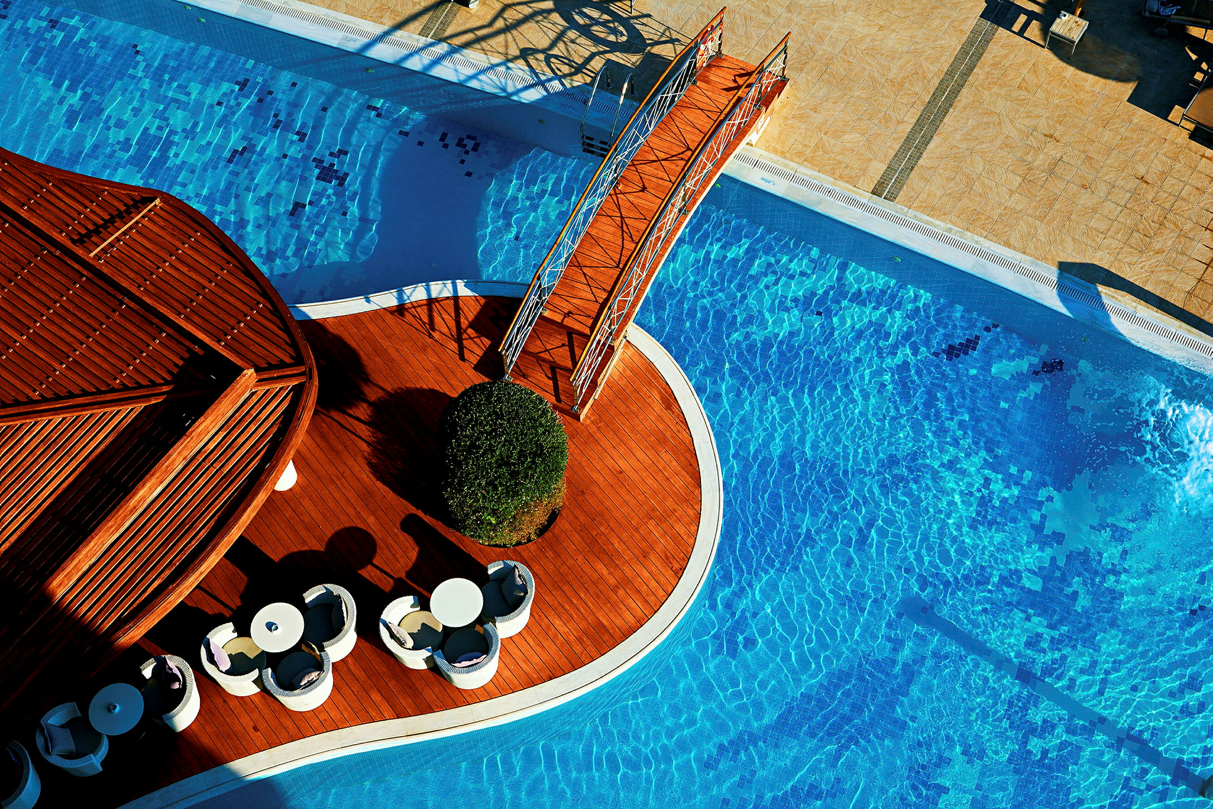 Vy ovanifrån av en pool med en träbro och en sittgrupp. (AI-genererad text)