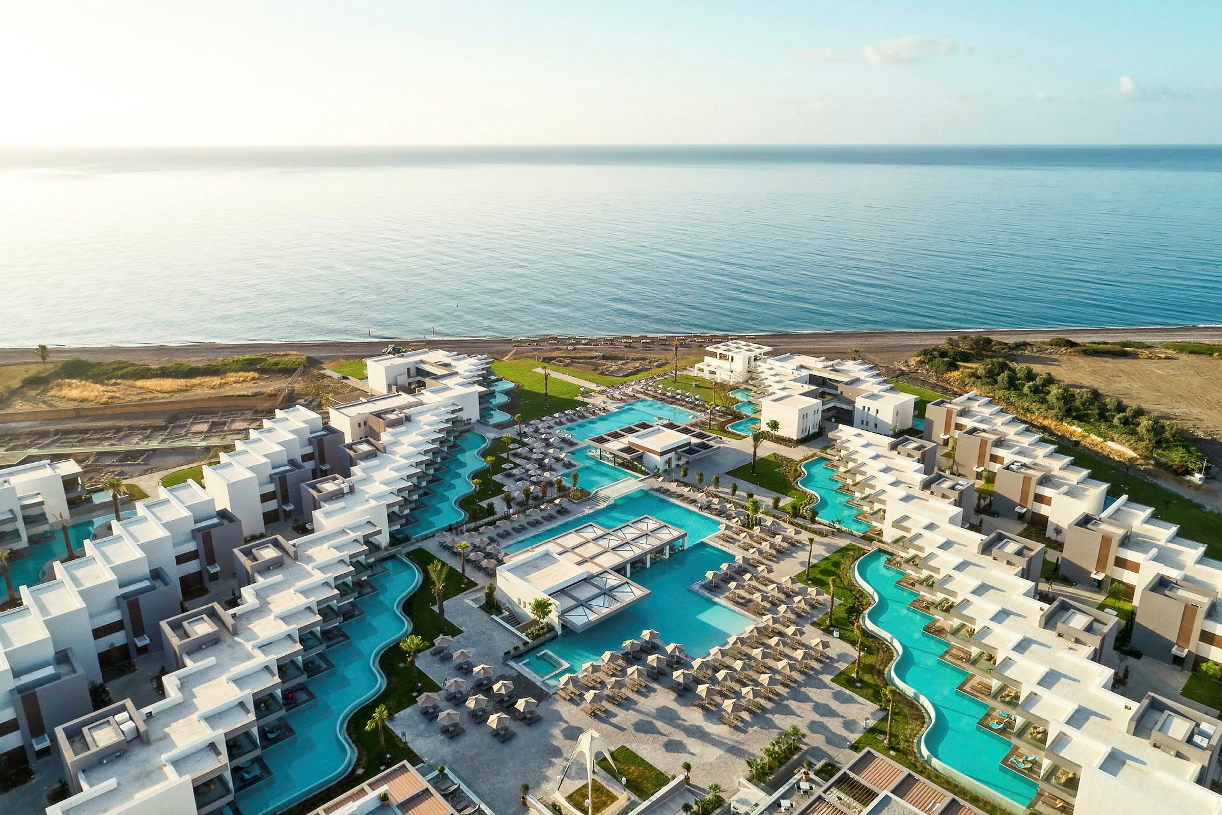 Flygfoto över ett hotell resort med pooler nära havet. (AI-genererad text)