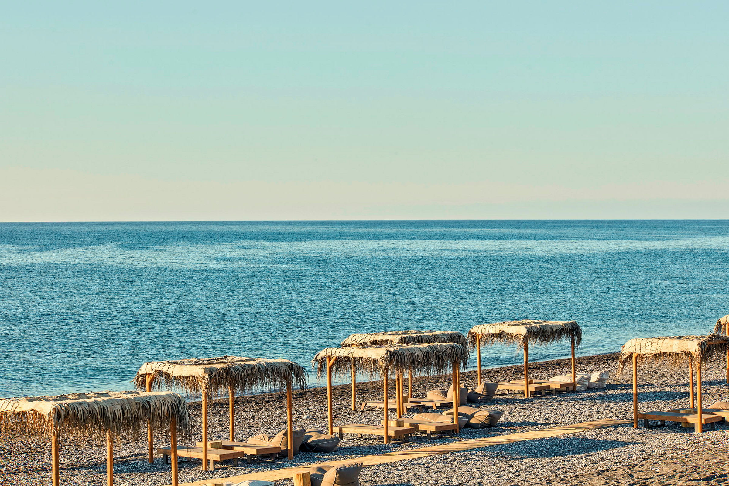 Strand med parasoller och solsängar vid havet. (AI-genererad text)