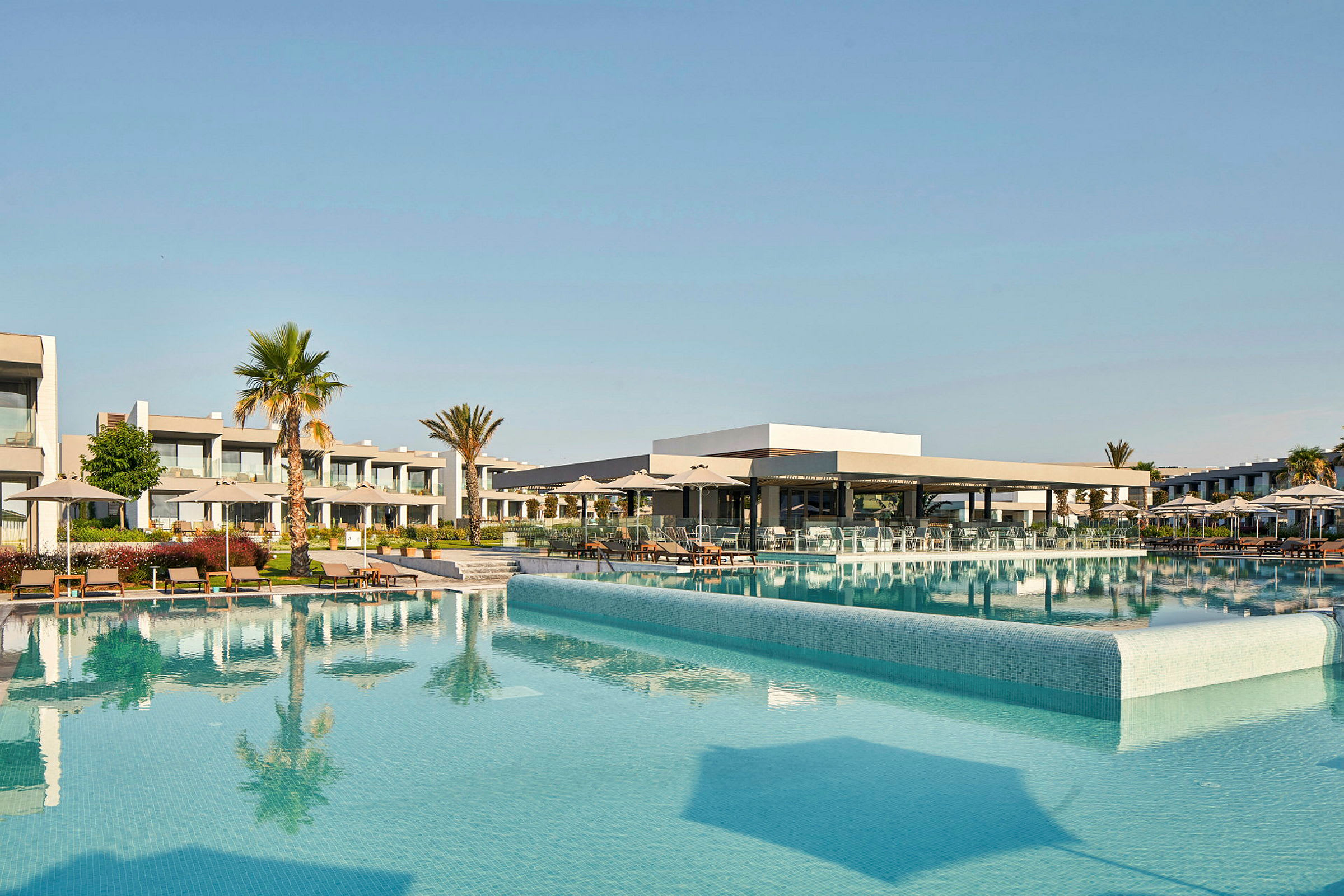 Bild av en hotellpool med omgivande solstolar och byggnader. (AI-genererad text)