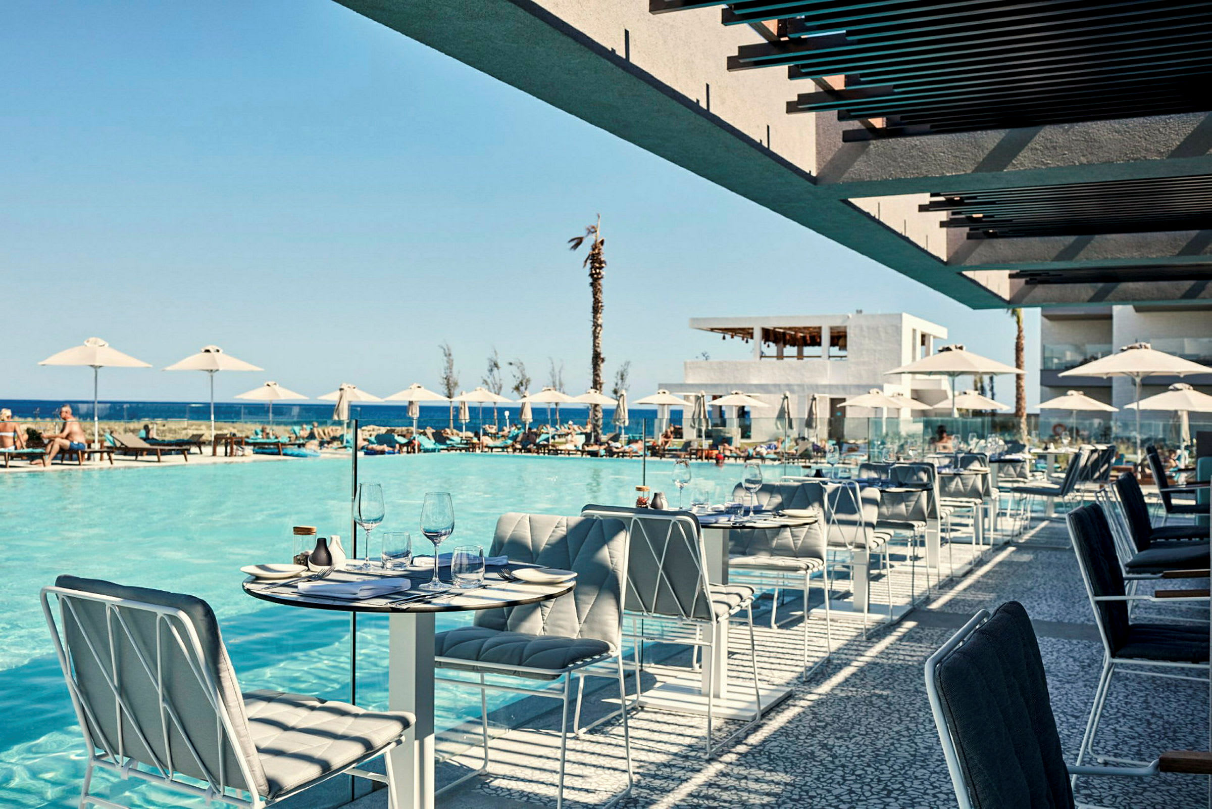 Uteservering med utsikt över en pool och havet i bakgrunden. (AI-genererad text)