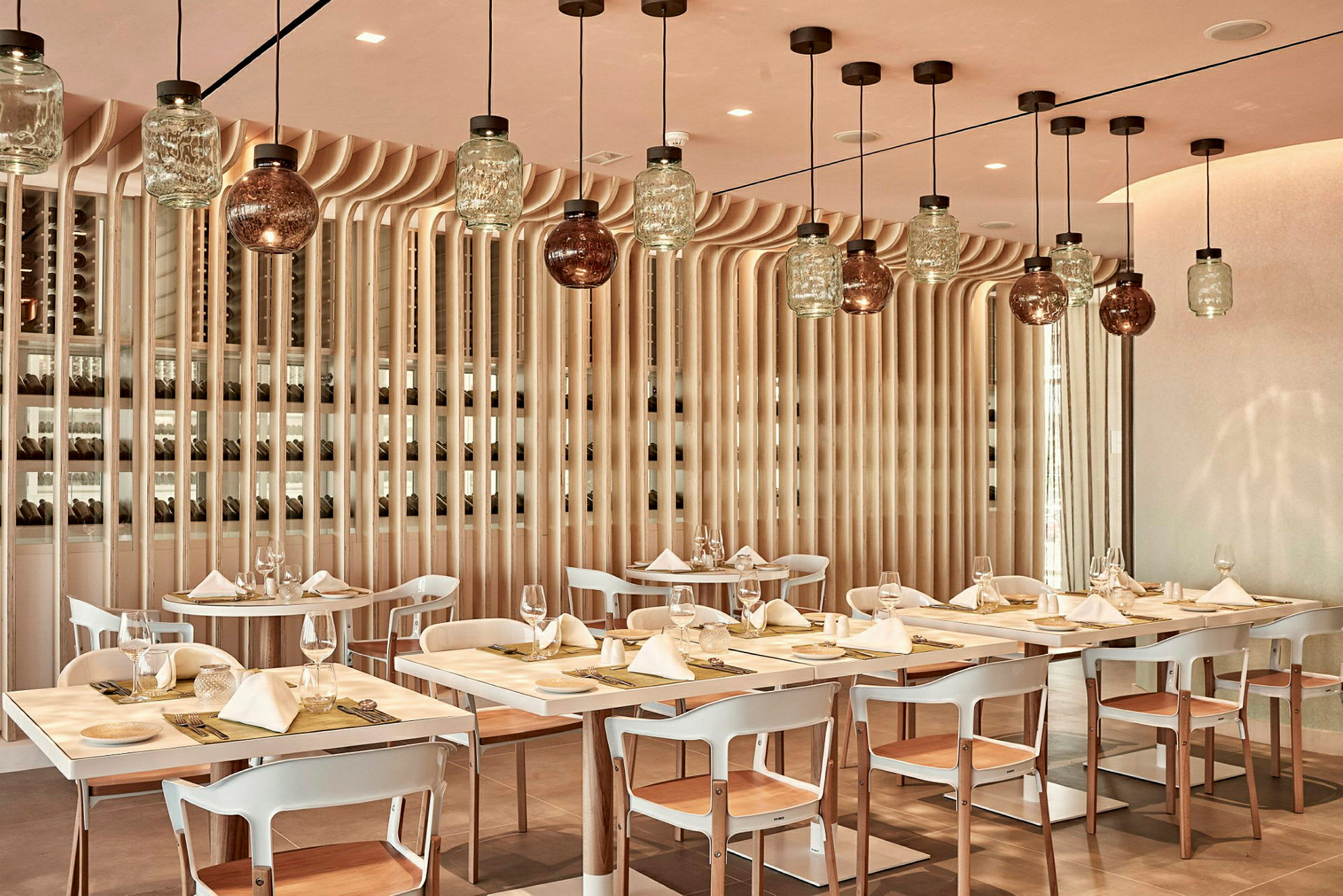 En restauranginteriör med dukade bord och moderna hängande lampor. (AI-genererad text)