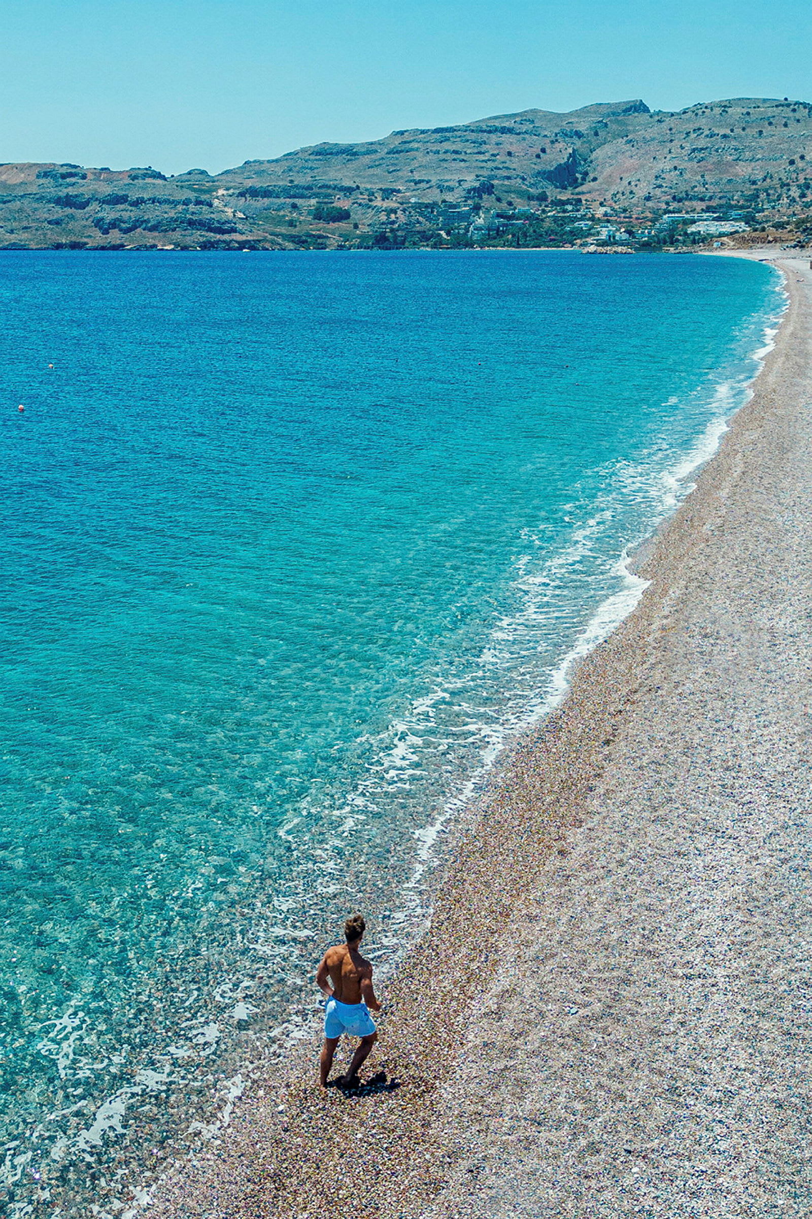En person går på en stenig strand nära havet. (AI-genererad text)