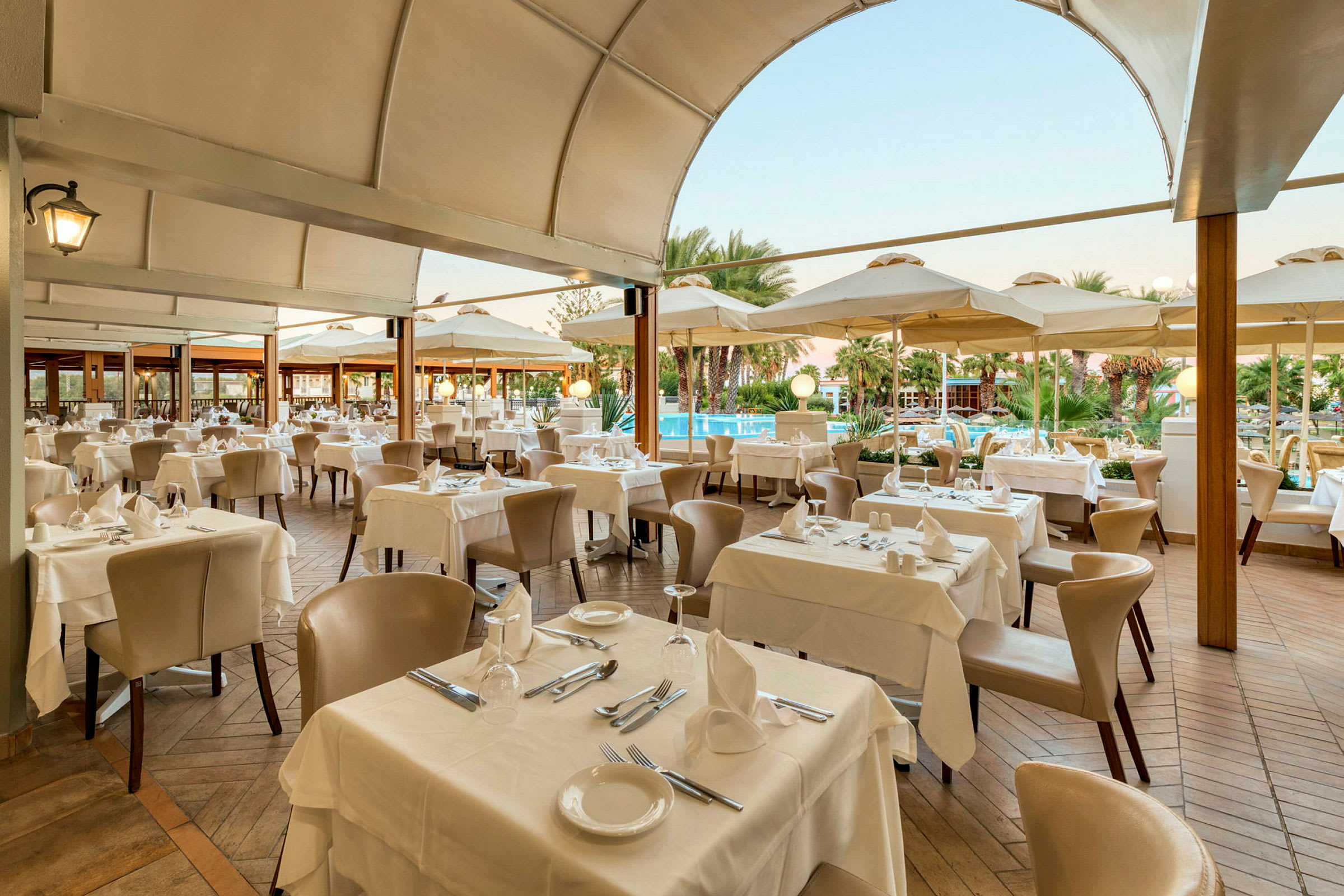 Restaurang med dukade bord och stolar under en täckt terrass. (AI-genererad text)