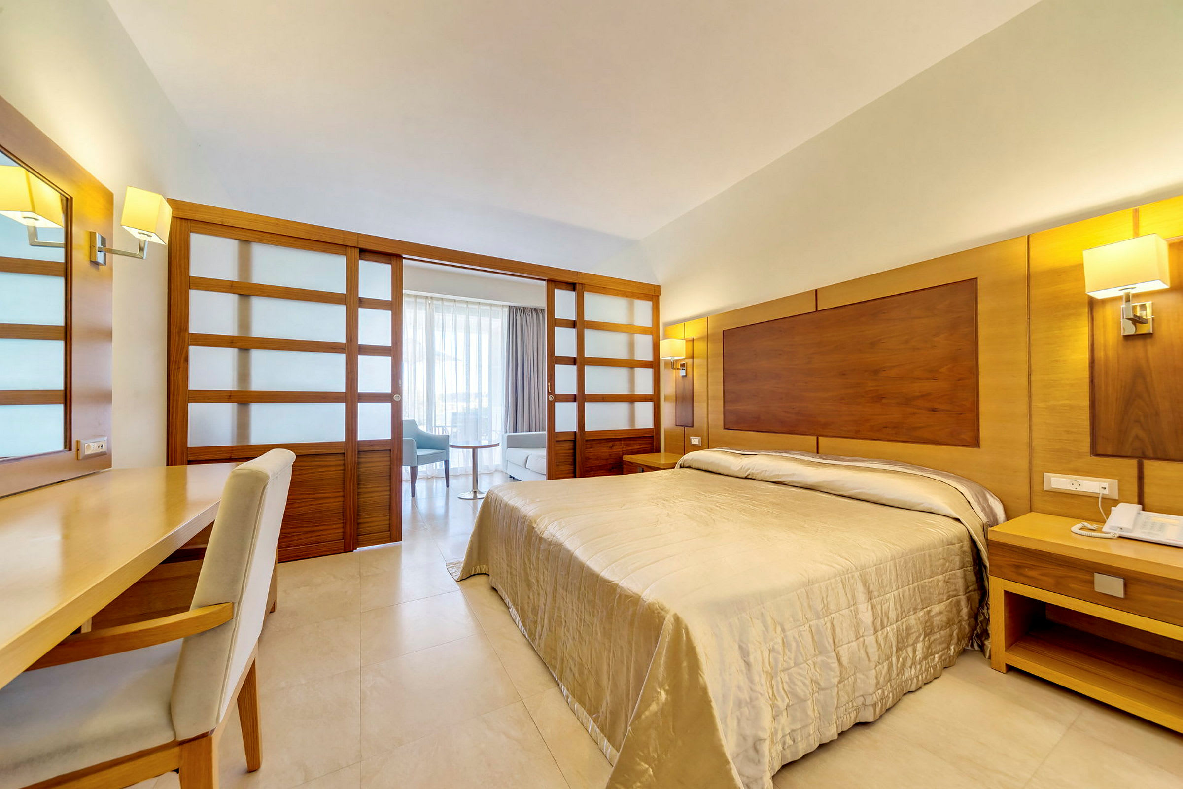 Ett hotellrum med en dubbelsäng, ett skrivbord med stol och ett sittutrymme i bakgrunden. (AI-genererad text)