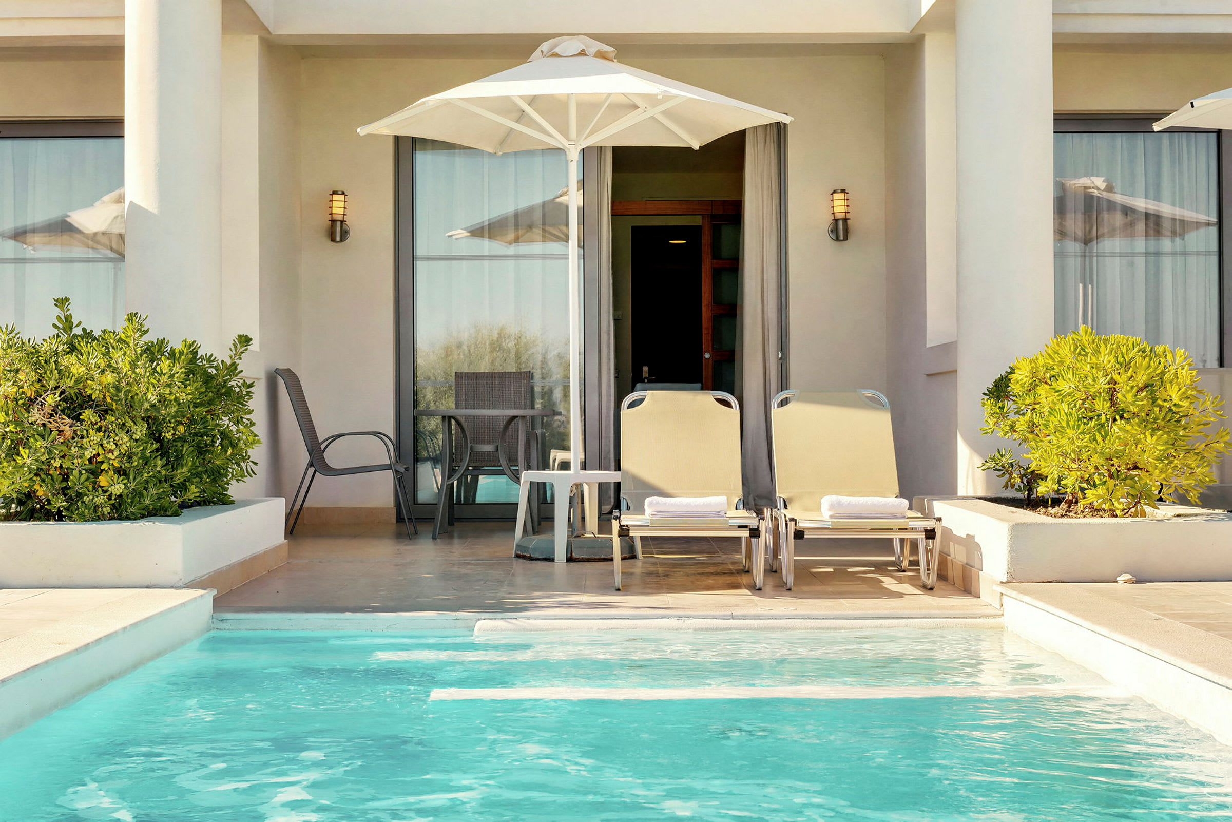 En privat terrass med solstolar, parasoll och en liten pool. (AI-genererad text)