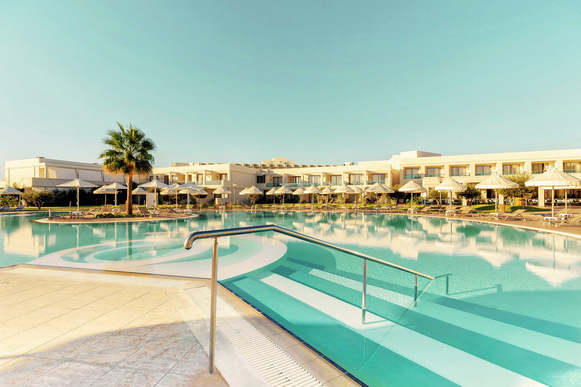 Utomhuspool med parasoller och solstolar, hotellbyggnad i bakgrunden. (AI-genererad text)