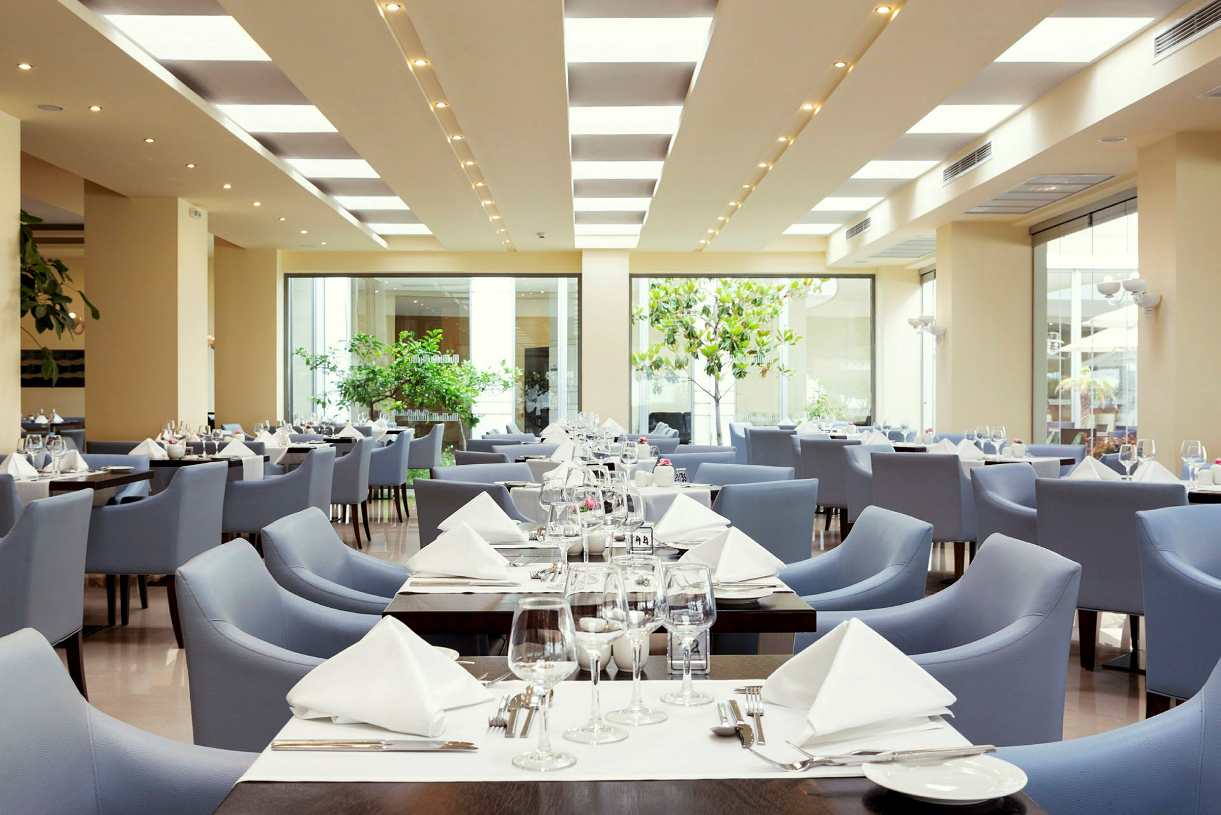 Bild av en modern restaurang med bord dukade och blå stolar. (AI-genererad text)