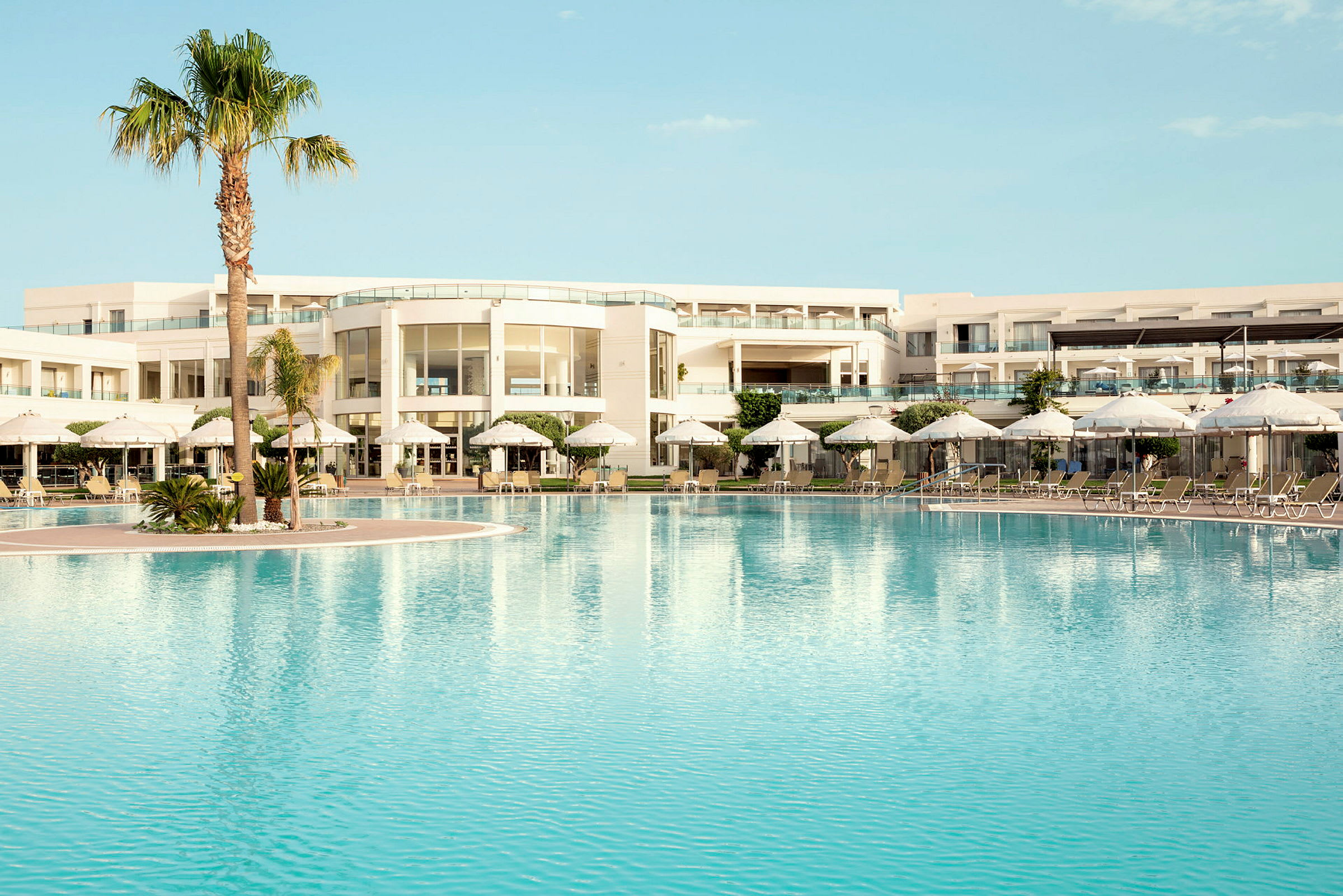 Poolområde vid en modern hotellbyggnad med solsängar och parasoller. (AI-genererad text)