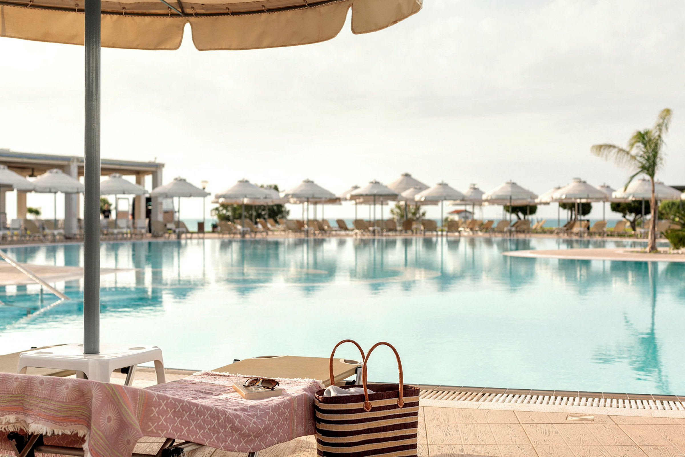 Solstol vid en pool med parasoller i bakgrunden. (AI-genererad text)