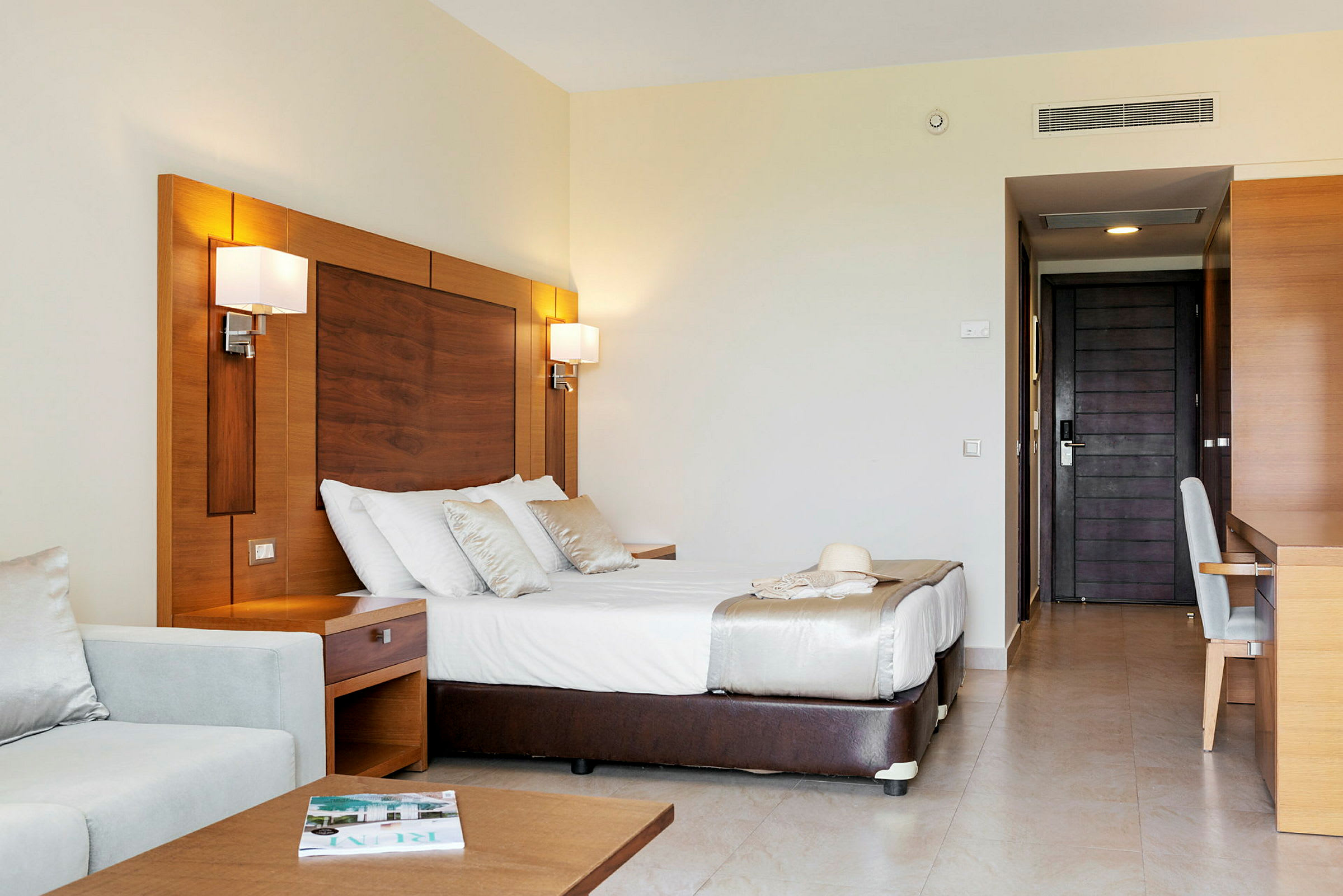 Ett hotellrum med en dubbelsäng, en soffa och ett skrivbord. (AI-genererad text)