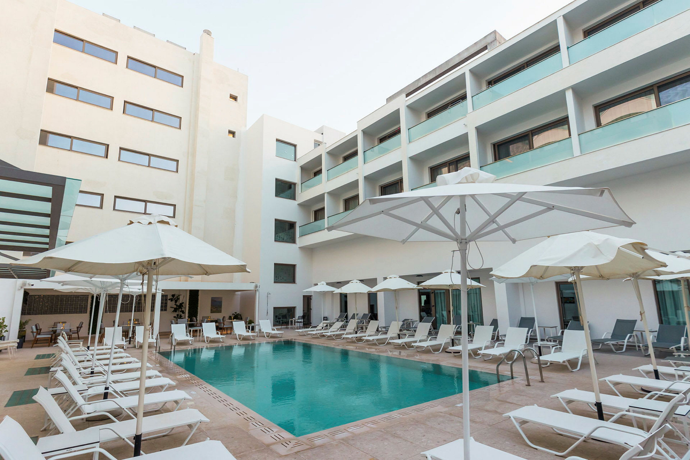 En hotellpool omgiven av solstolar och parasoller. (AI-genererad text)