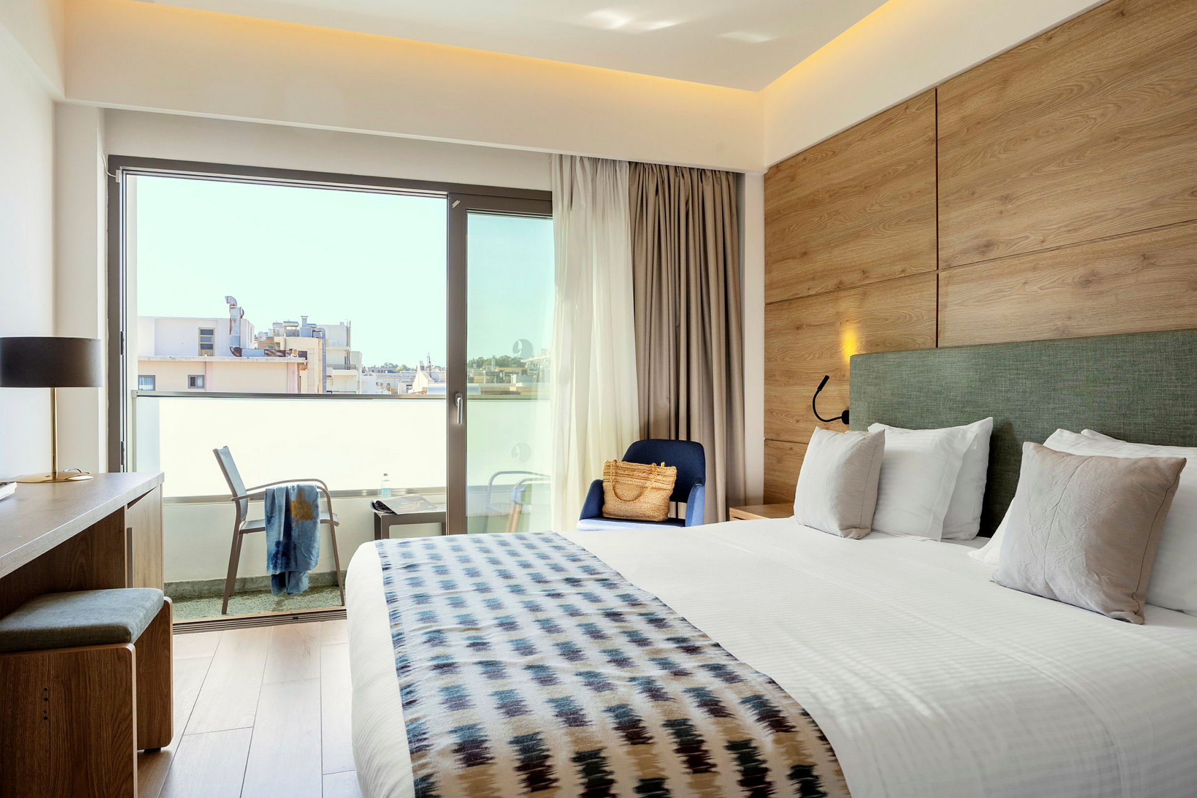Ett hotellrum med en stor säng, skrivbord, stol och balkong. (AI-genererad text)