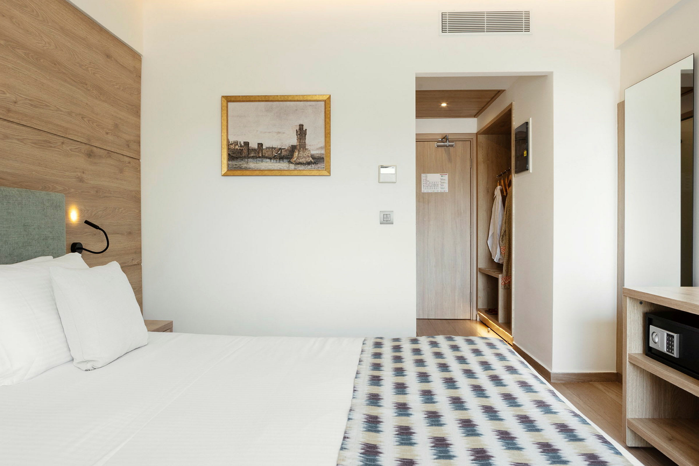 Ett hotellrum med säng, väggmålning och en öppen garderob. (AI-genererad text)