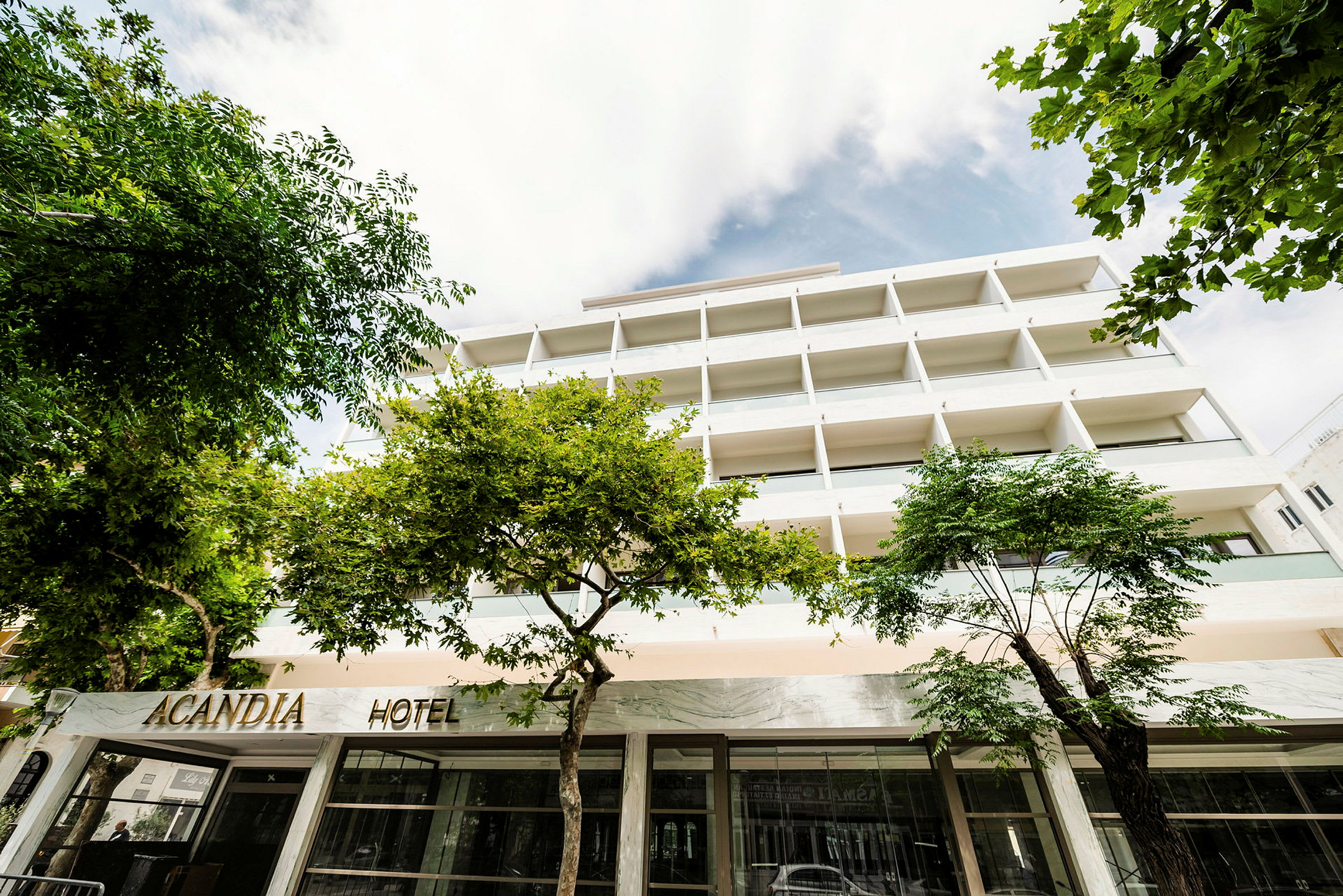 Bild på hotellet Acandia med fasaden och omgivande träd. (AI-genererad text)
