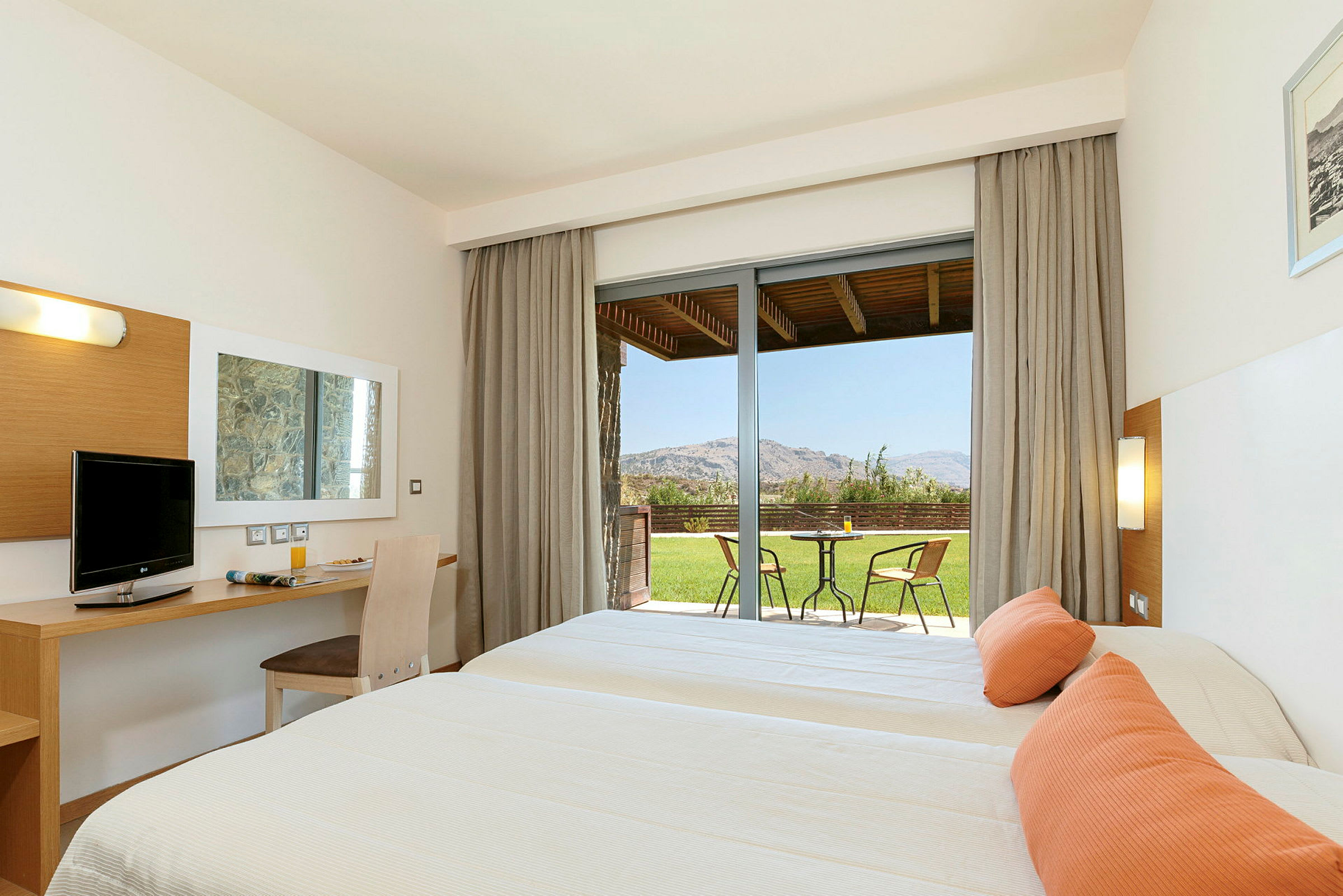 Ett hotellrum med två sängar och en sittgrupp på terrassen med utsikt över en trädgård. (AI-genererad text)