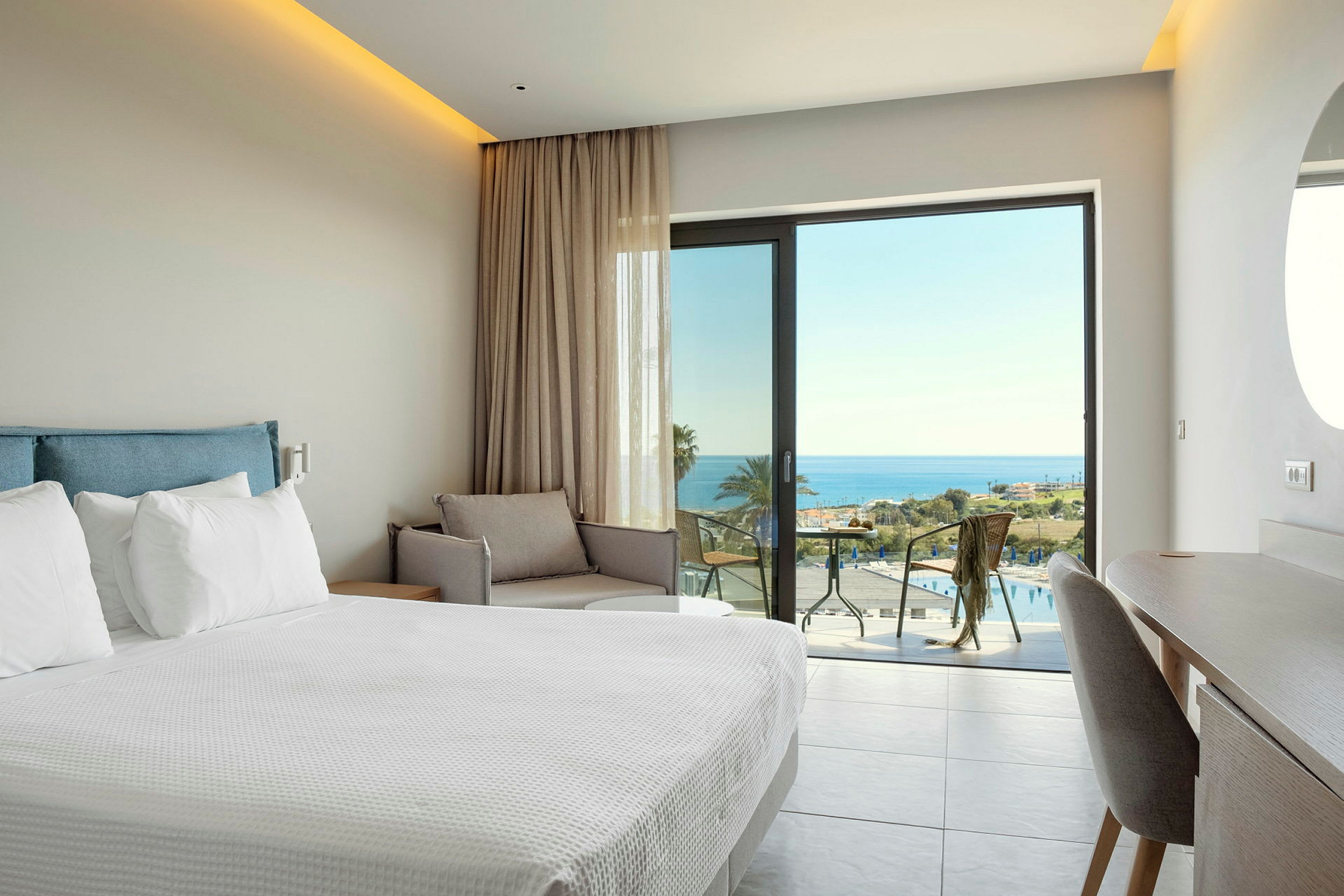 Hotellrum med säng, soffa och utsikt över havet. (AI-genererad text)