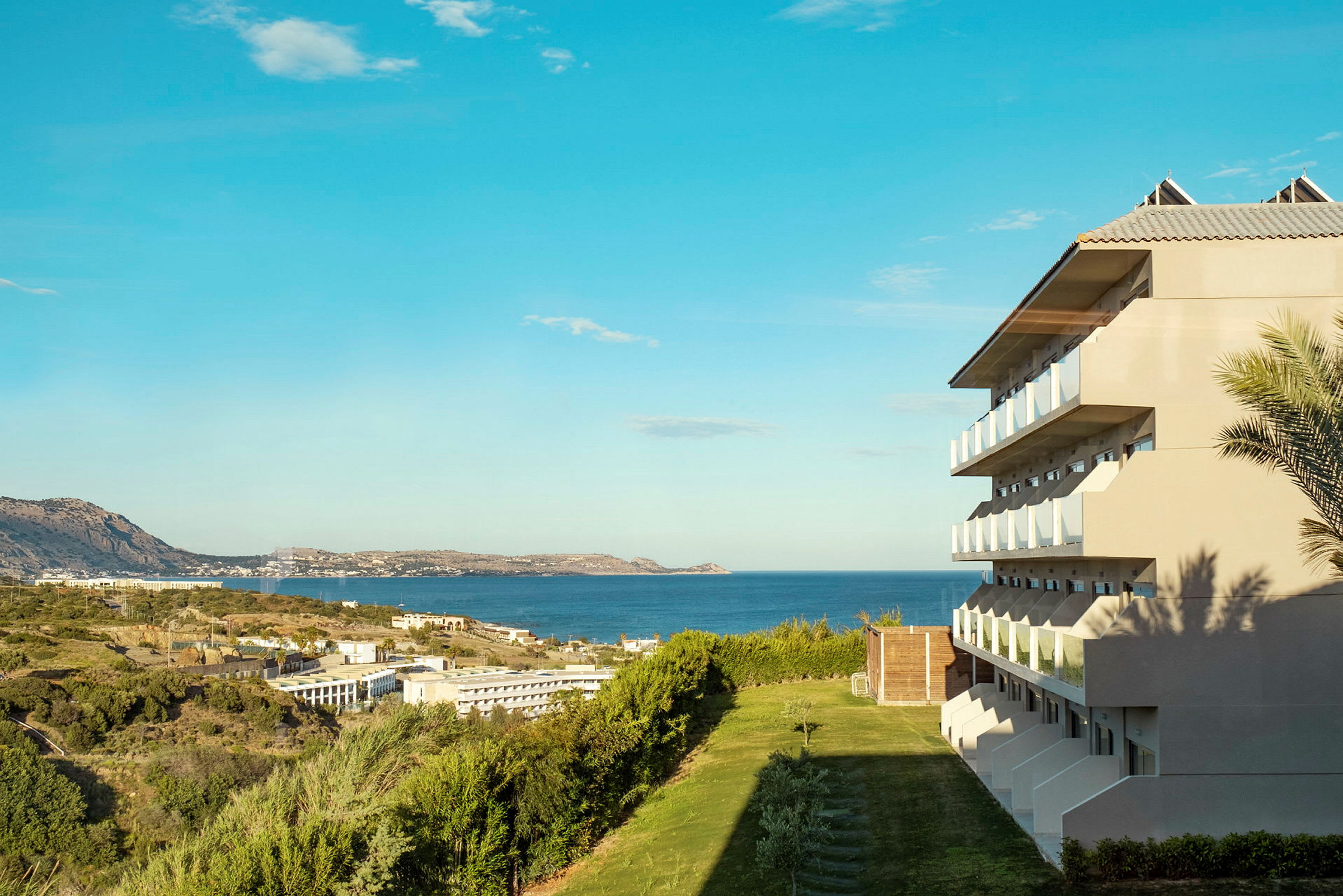 Bild av ett hotell med balkonger med utsikt över havet och grönområden. (AI-genererad text)