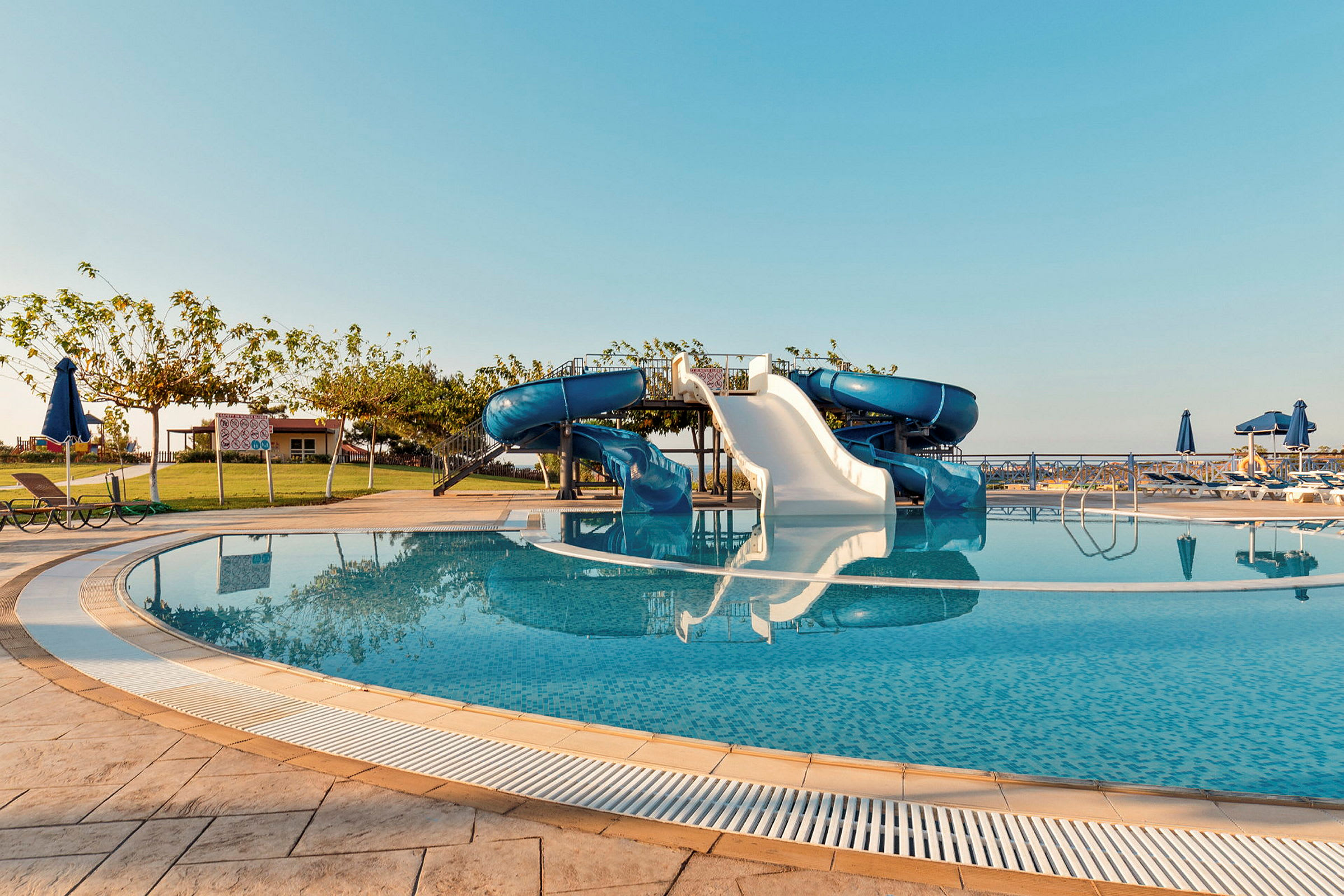 Pool med vattenrutschbanor under klar himmel. (AI-genererad text)