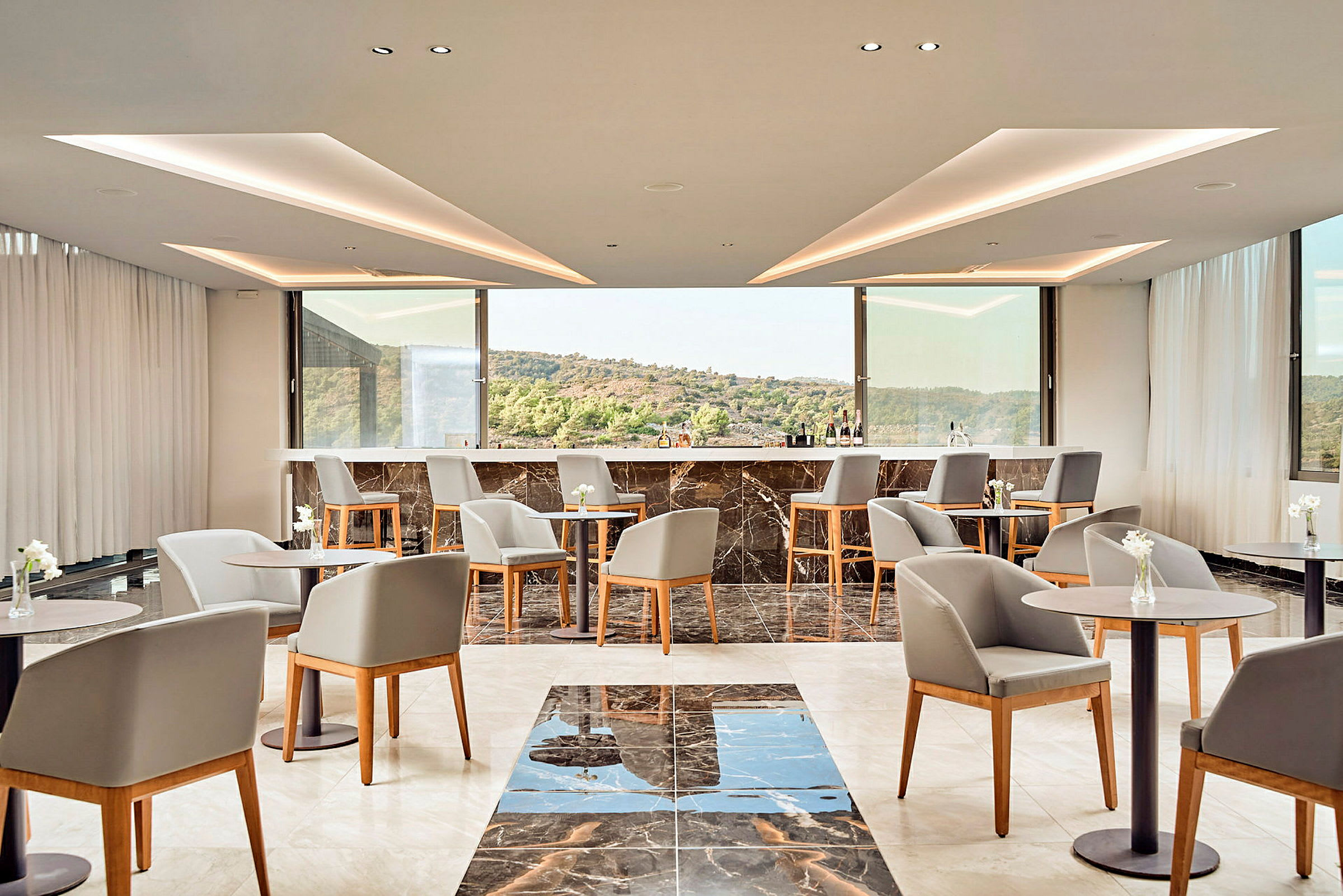 En modern lounge med bord och stolar samt en bar i bakgrunden. (AI-genererad text)
