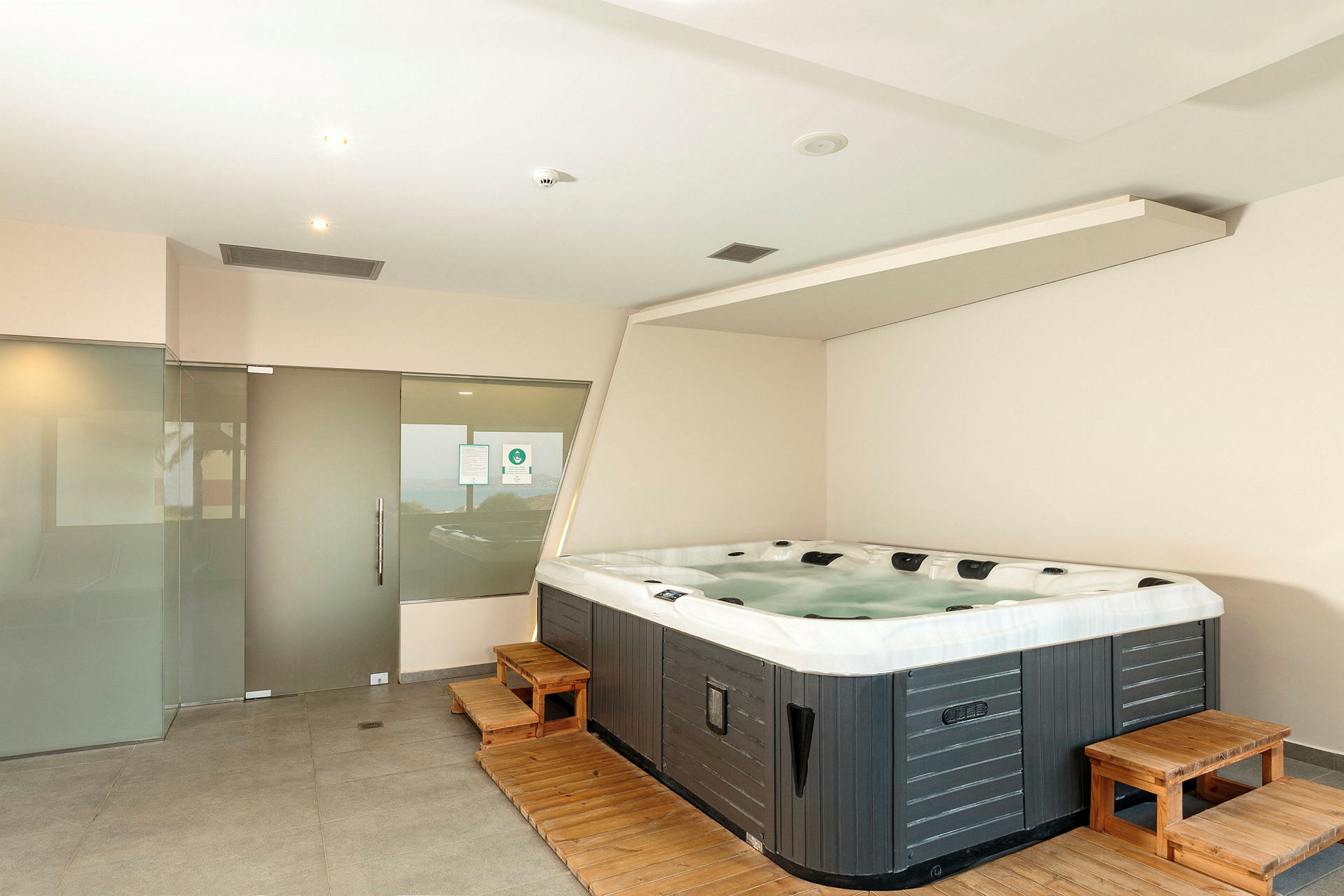 Ett rum med en jacuzzi och glasdörrar. (AI-genererad text)