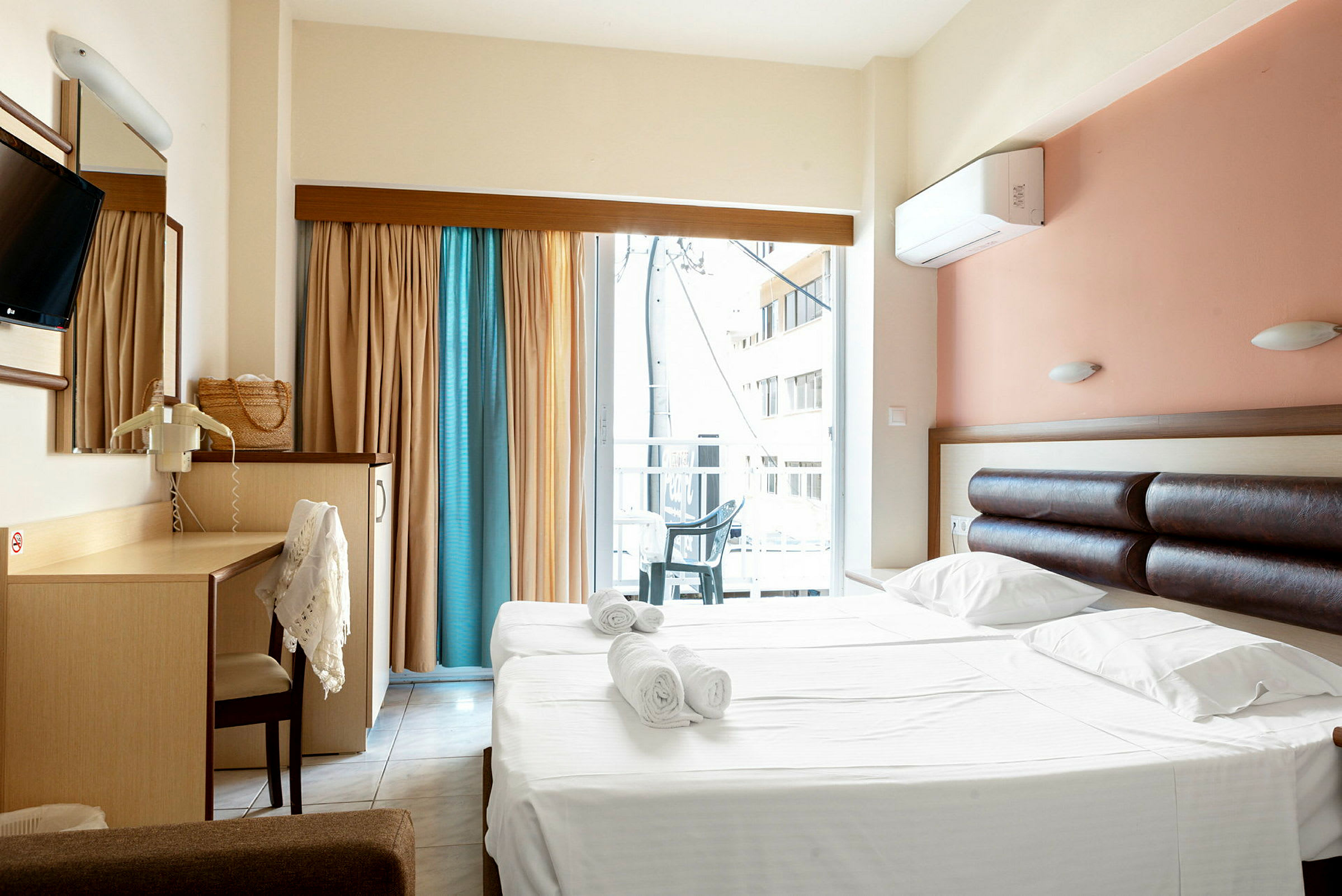 Hotellrum med dubbelsäng och skrivbord, samt balkong med utsikt. (AI-genererad text)