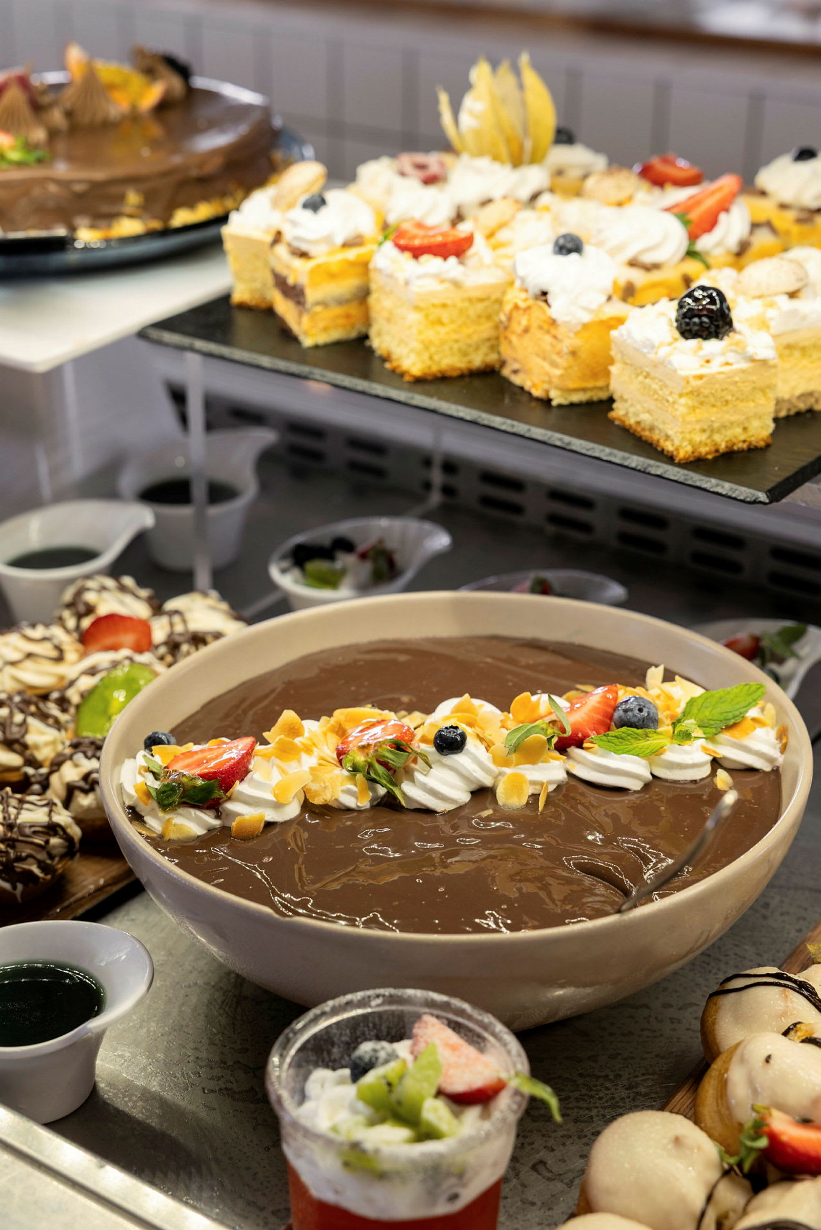 En buffé med olika desserter, inklusive chokladpudding garnerad med frukt och grädde. (AI-genererad text)