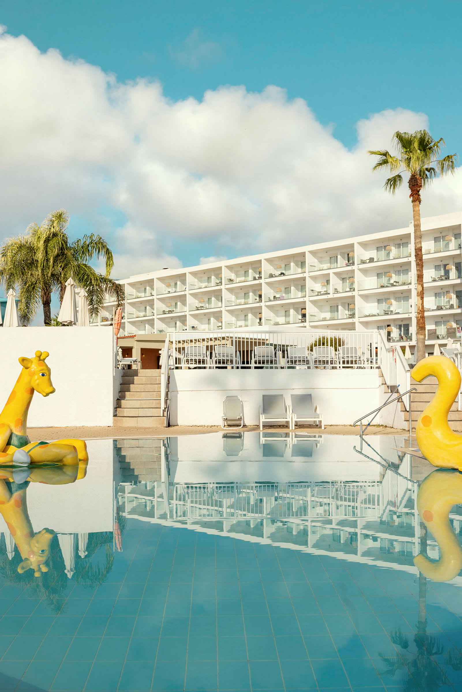 Bild av ett hotell med en pool som har två gula uppblåsbara leksaker. (AI-genererad text)