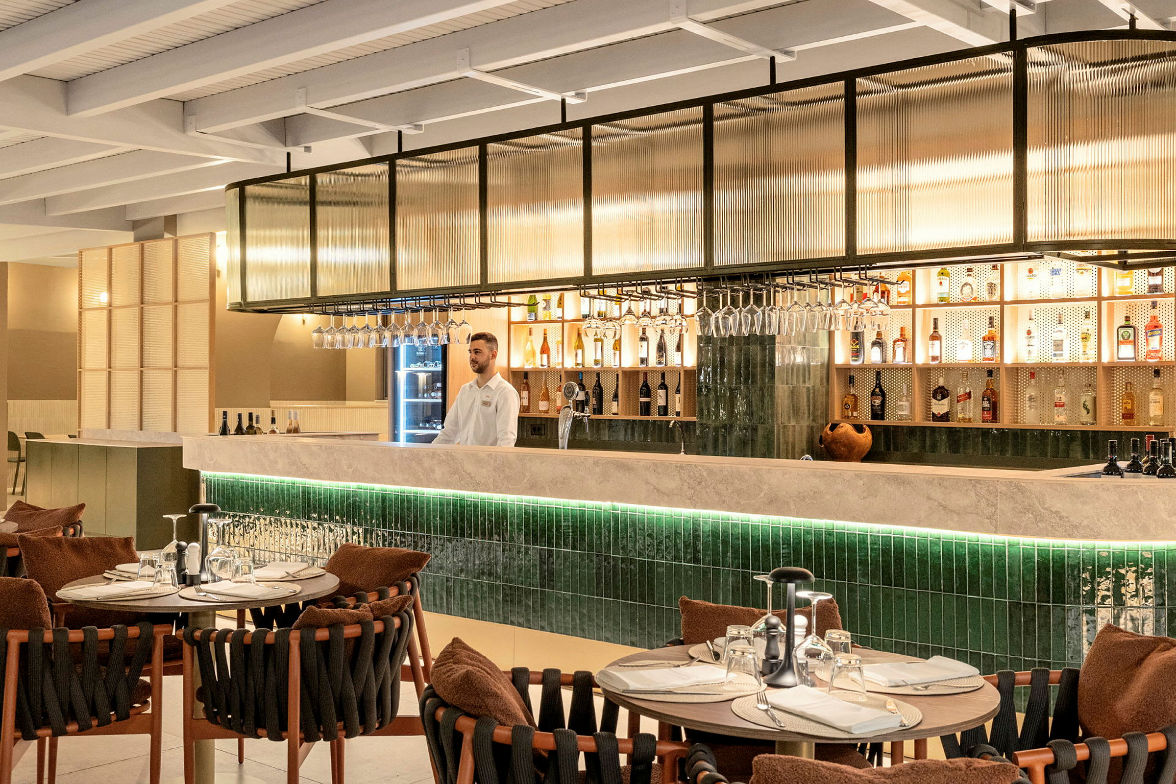 En inredd restaurang med ett välfyllt barskåp och bord med dukade tallrikar. (AI-genererad text)
