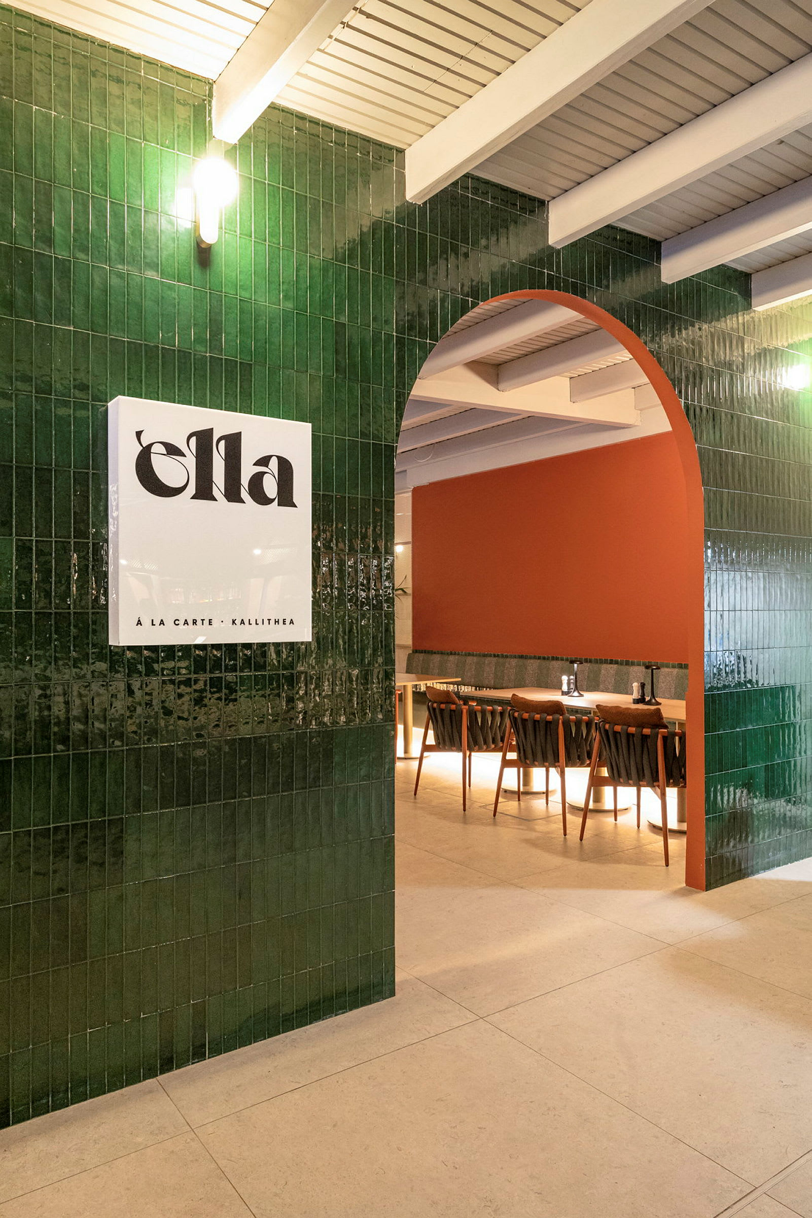 En välkomnande restauranginteriör med en grön kaklad båge, en orangefärgad vägg och sittplatser. (AI-genererad text)