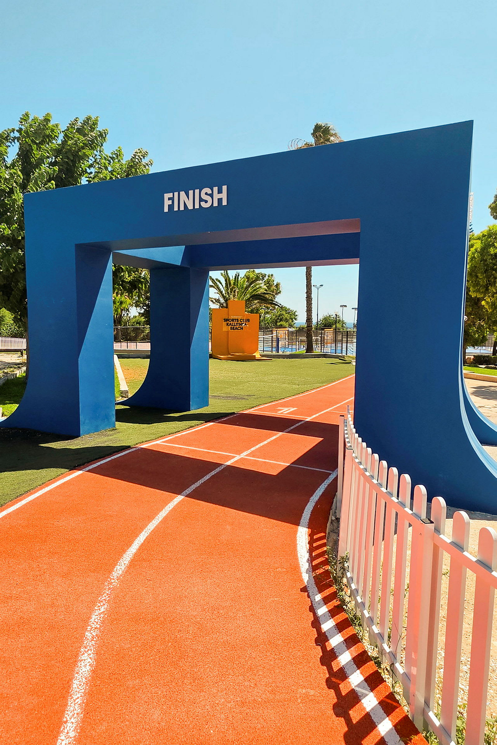 En blå målgångsport med texten "FINISH" över en orange löparbana med vita linjer. (AI-genererad text)
