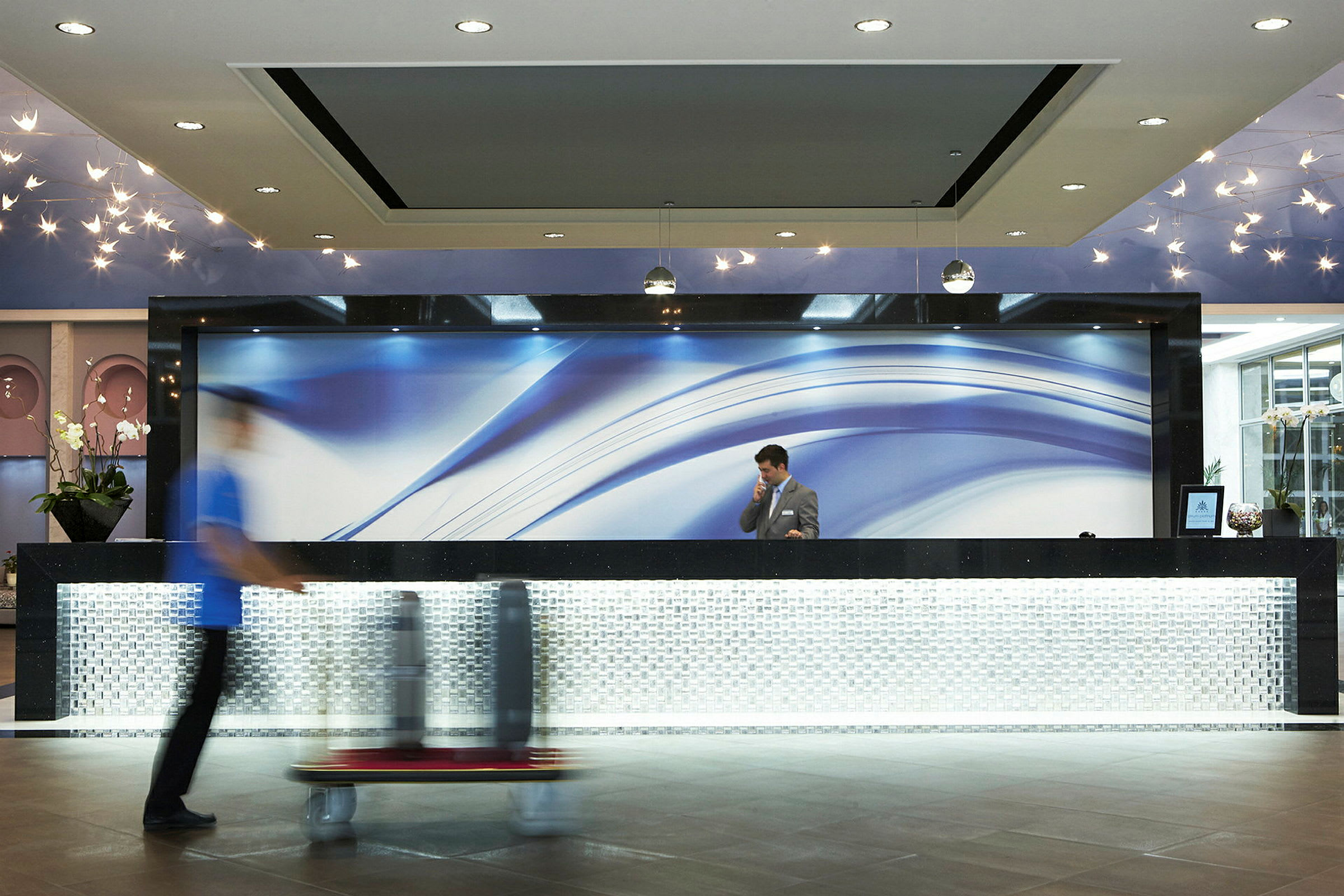 Hotellets reception med en modern designdisk och blå väggbakgrund. (AI-genererad text)
