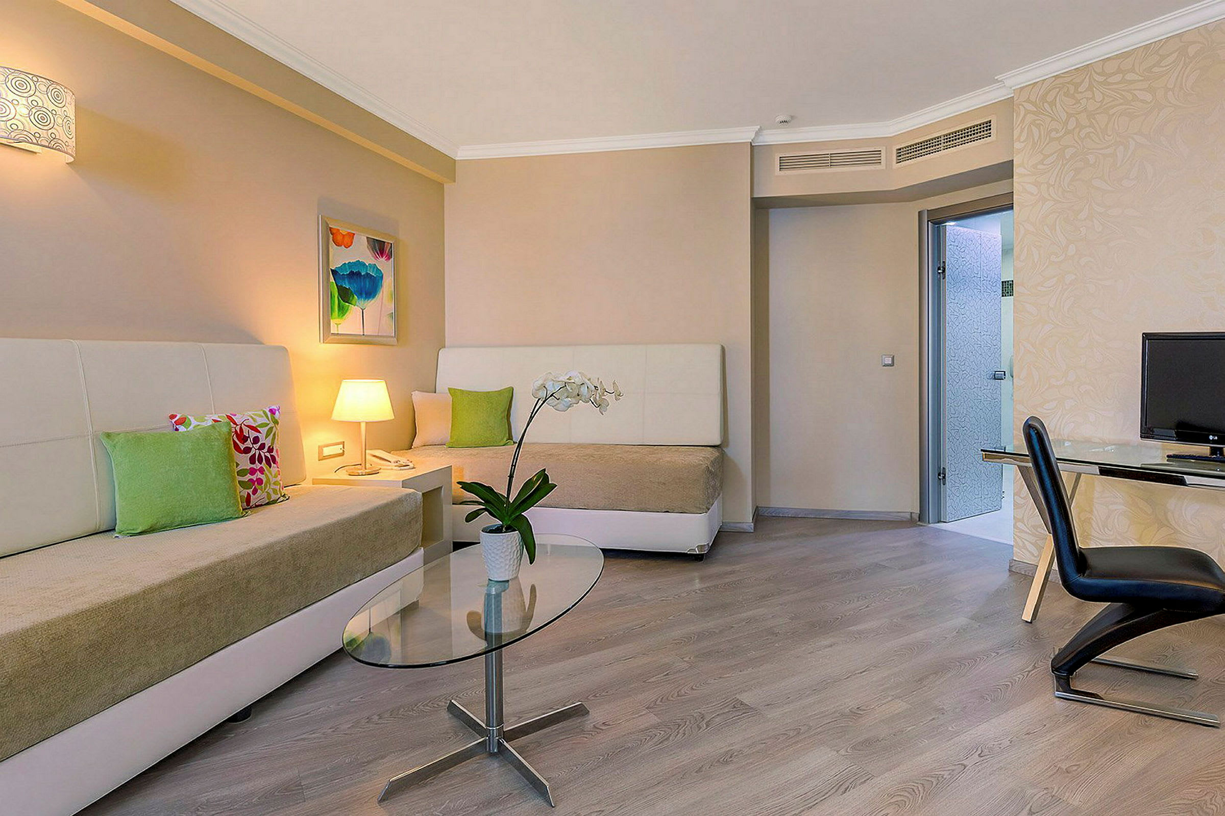 Ett hotellrum med två sängar, ett bord med en blomkruka och en arbetsyta med stol och TV. (AI-genererad text)