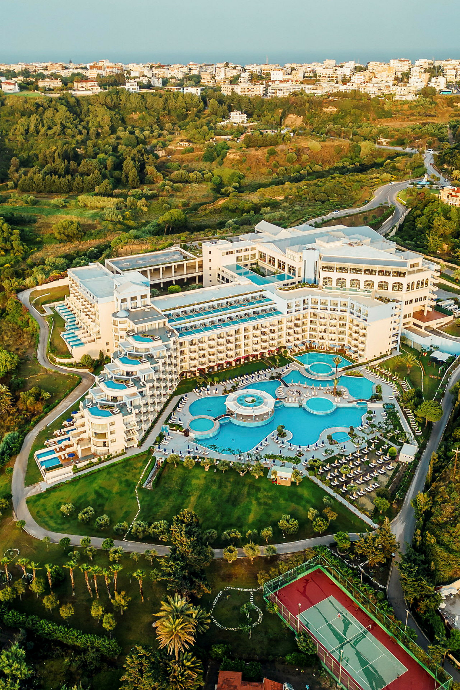 Flygfoto av ett hotell med poolområde och omgivande grönska. (AI-genererad text)