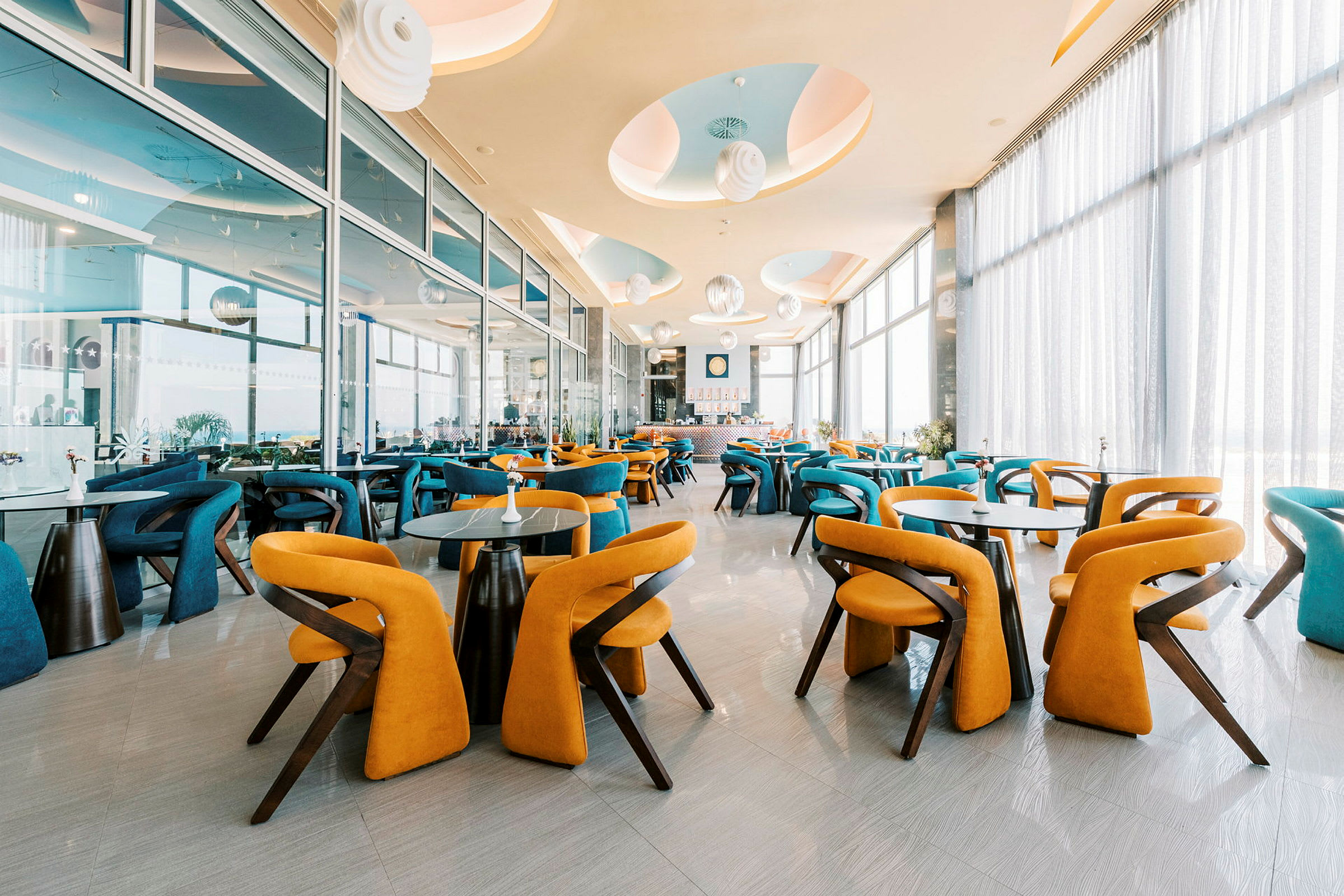 En modern restaurang med färgglada stolar och stora fönster. (AI-genererad text)